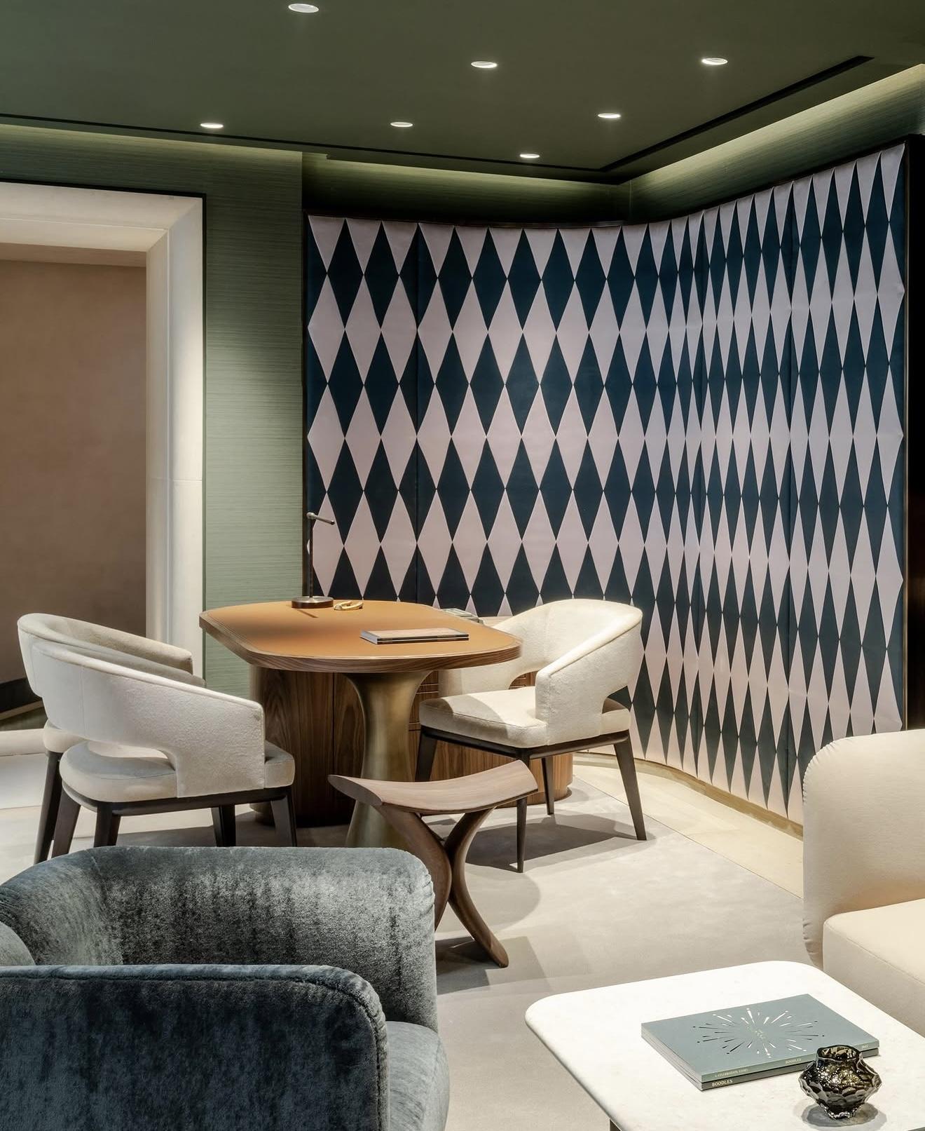 Private lounge inside The Boodles Townhouse with green walls, a black-and-white diamond-patterned screen, wooden table and upholstered seating
