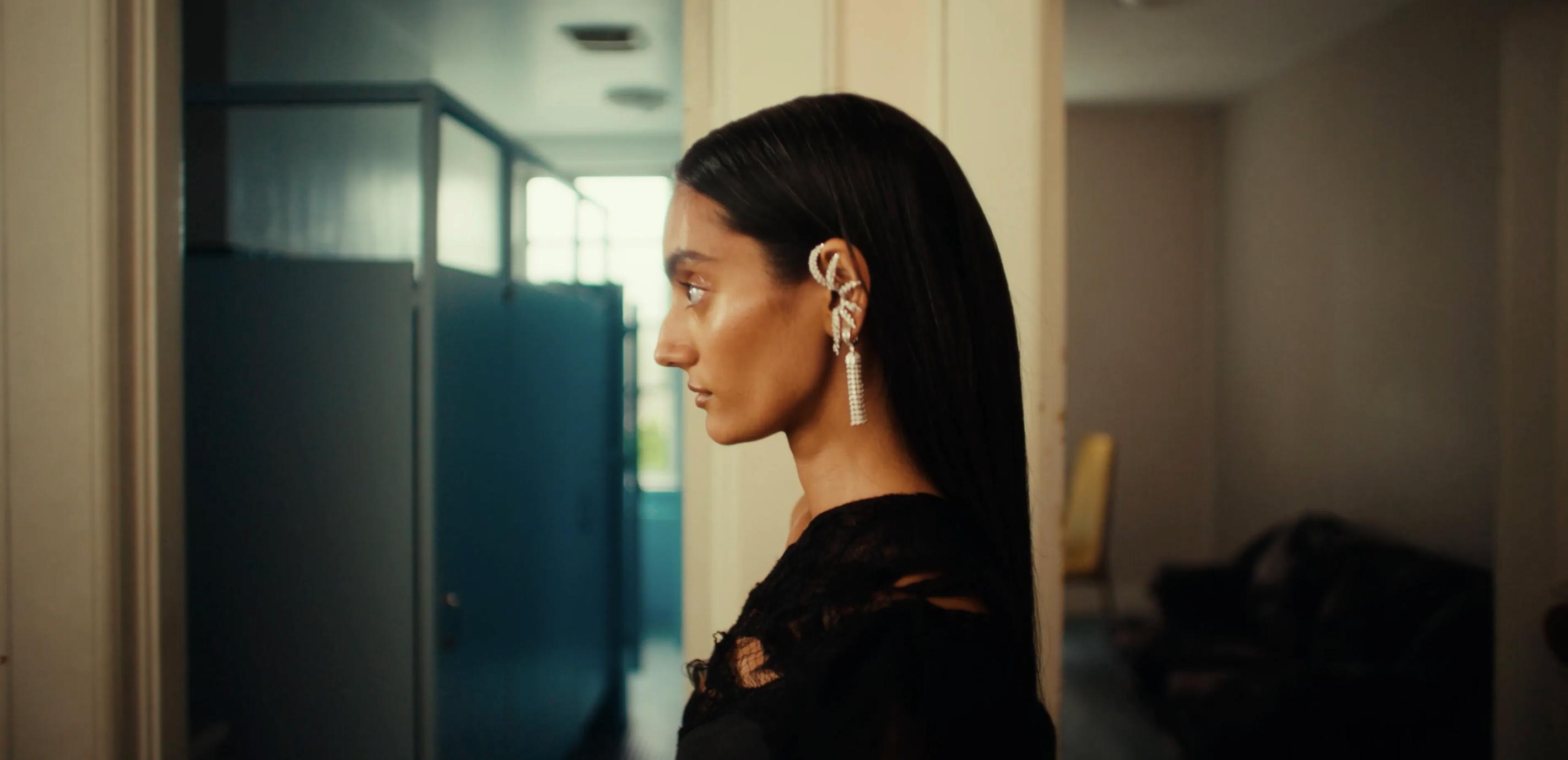 Model in profile wearing a sculptural diamond ear cuff and long diamond drop earring with a black outfit