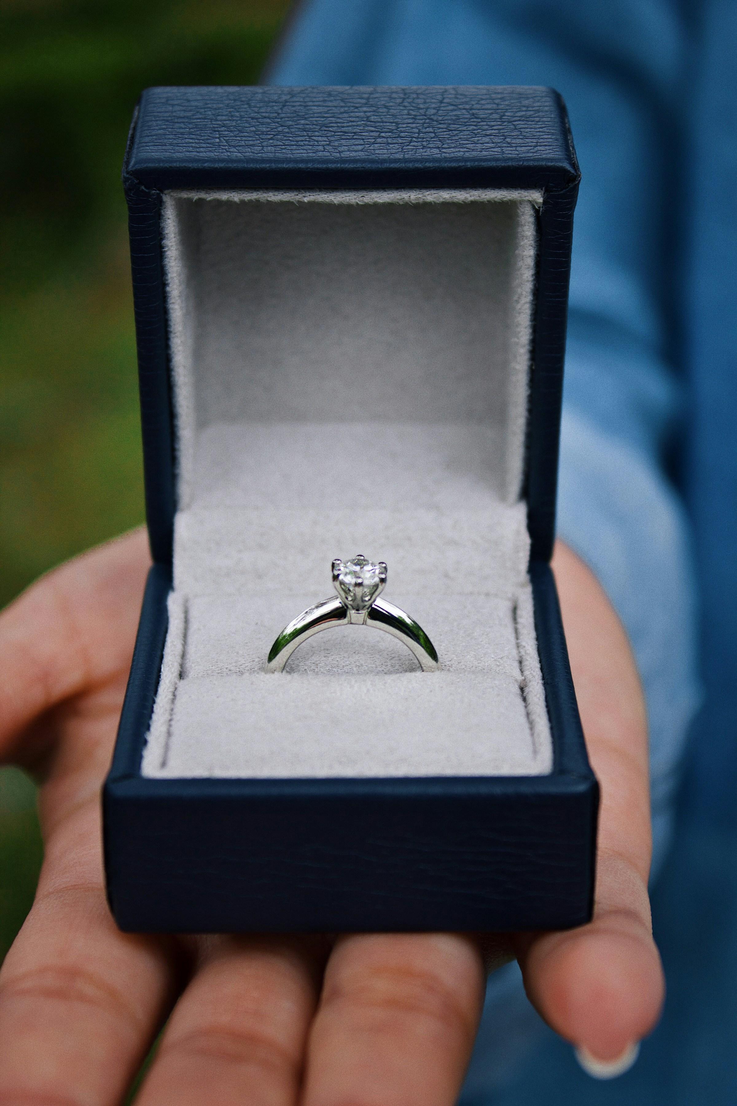 Diamond solitaire engagement ring presented in an open dark blue ring box. Source: Unsplash
