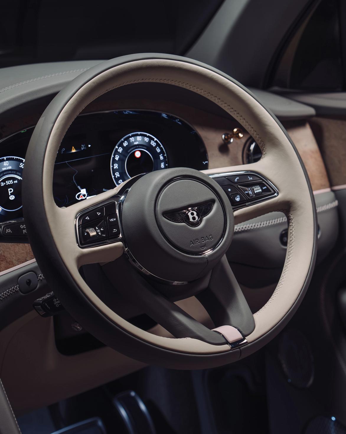 Bentley steering wheel and dashboard with digital display and leather interior detailing.