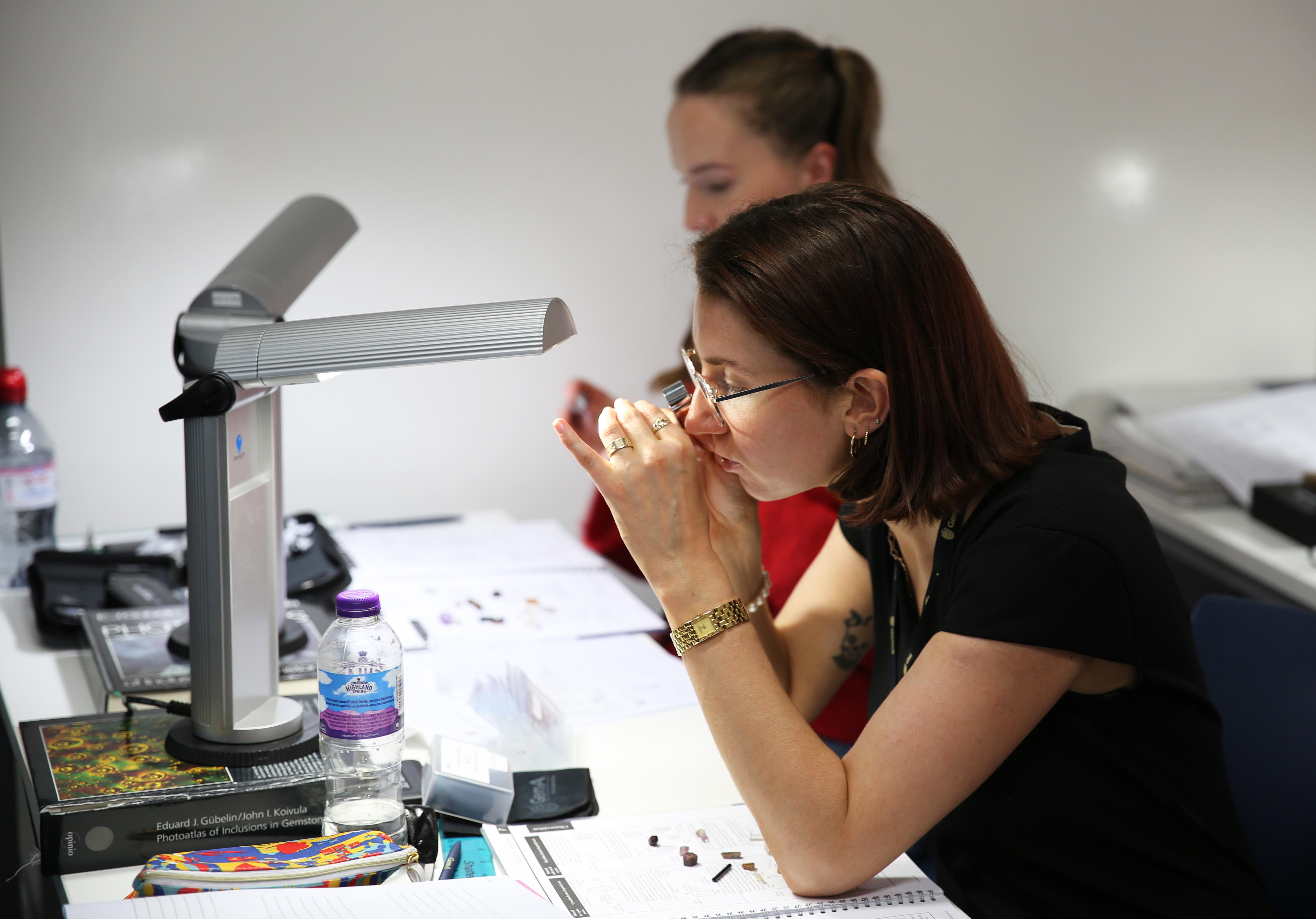 Gem-A student examining a gemstone with a loupe during a practical gemmology class in London.