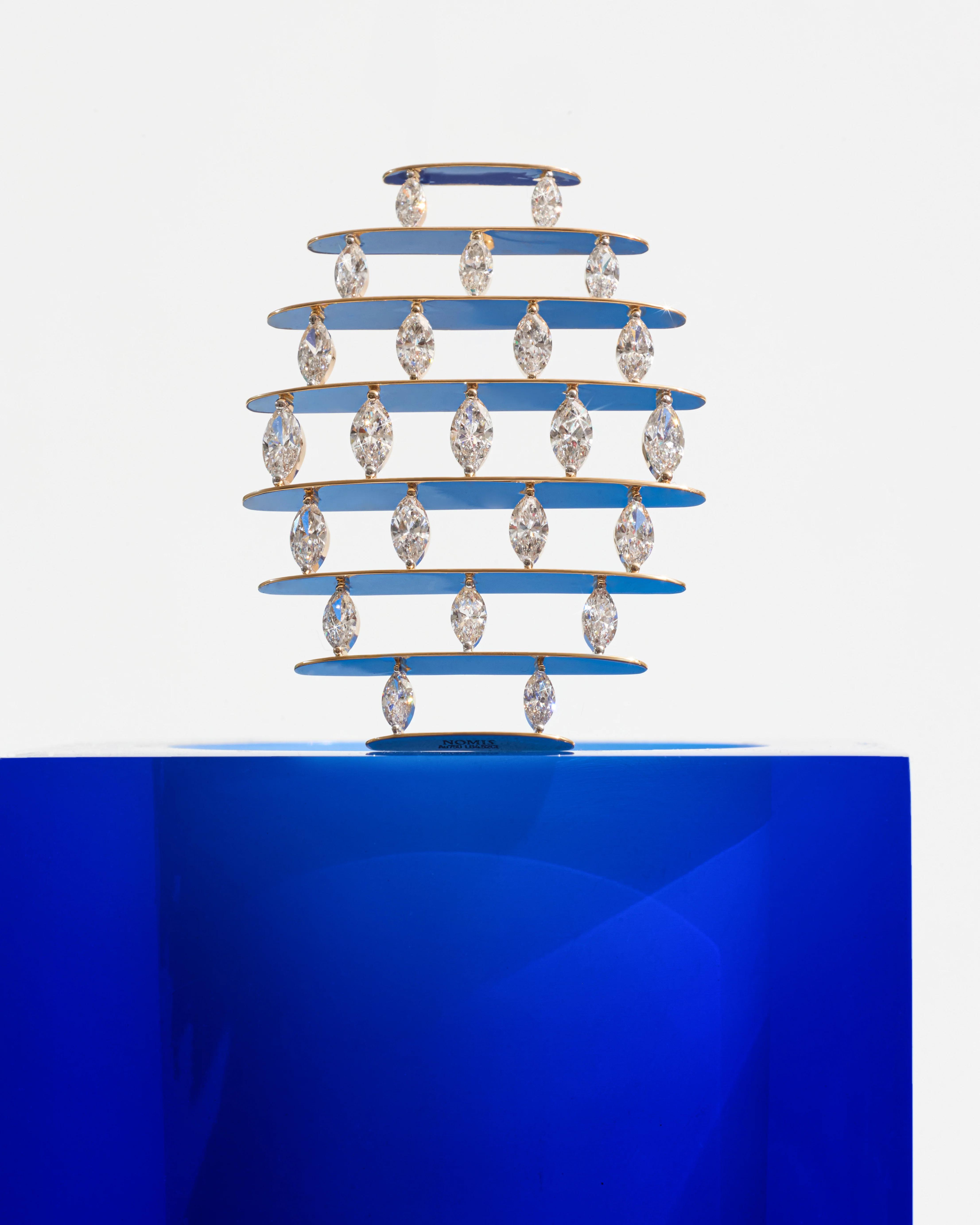 NOMIS L. Pape single earring with rows of yellow gold and marquise-cut lab-grown diamonds, displayed above a blue plinth