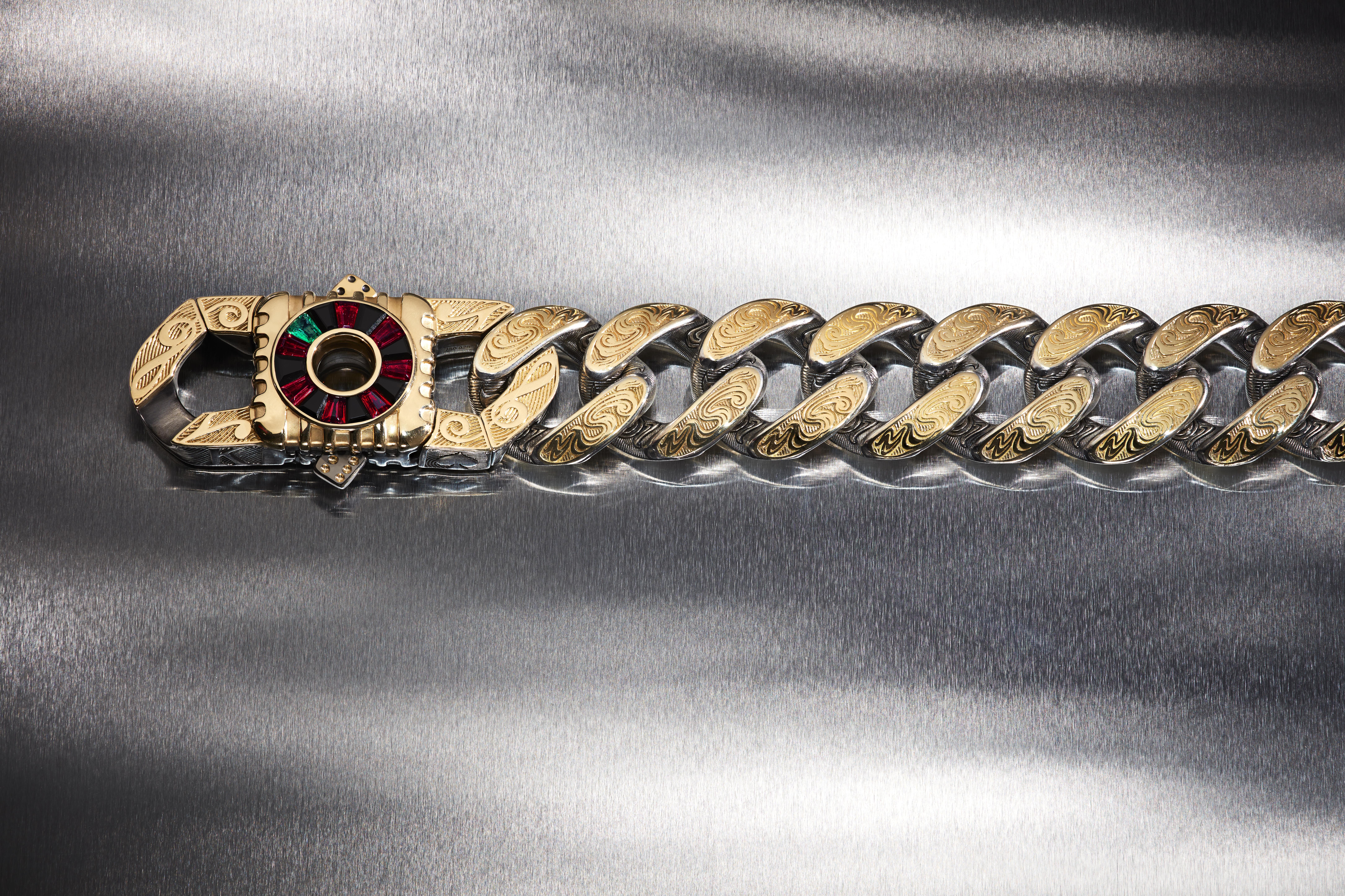 Stephen Webster’s Rat Race engraved Cuban-link bracelet with a roulette-wheel clasp set with black onyx, red garnets and emeralds