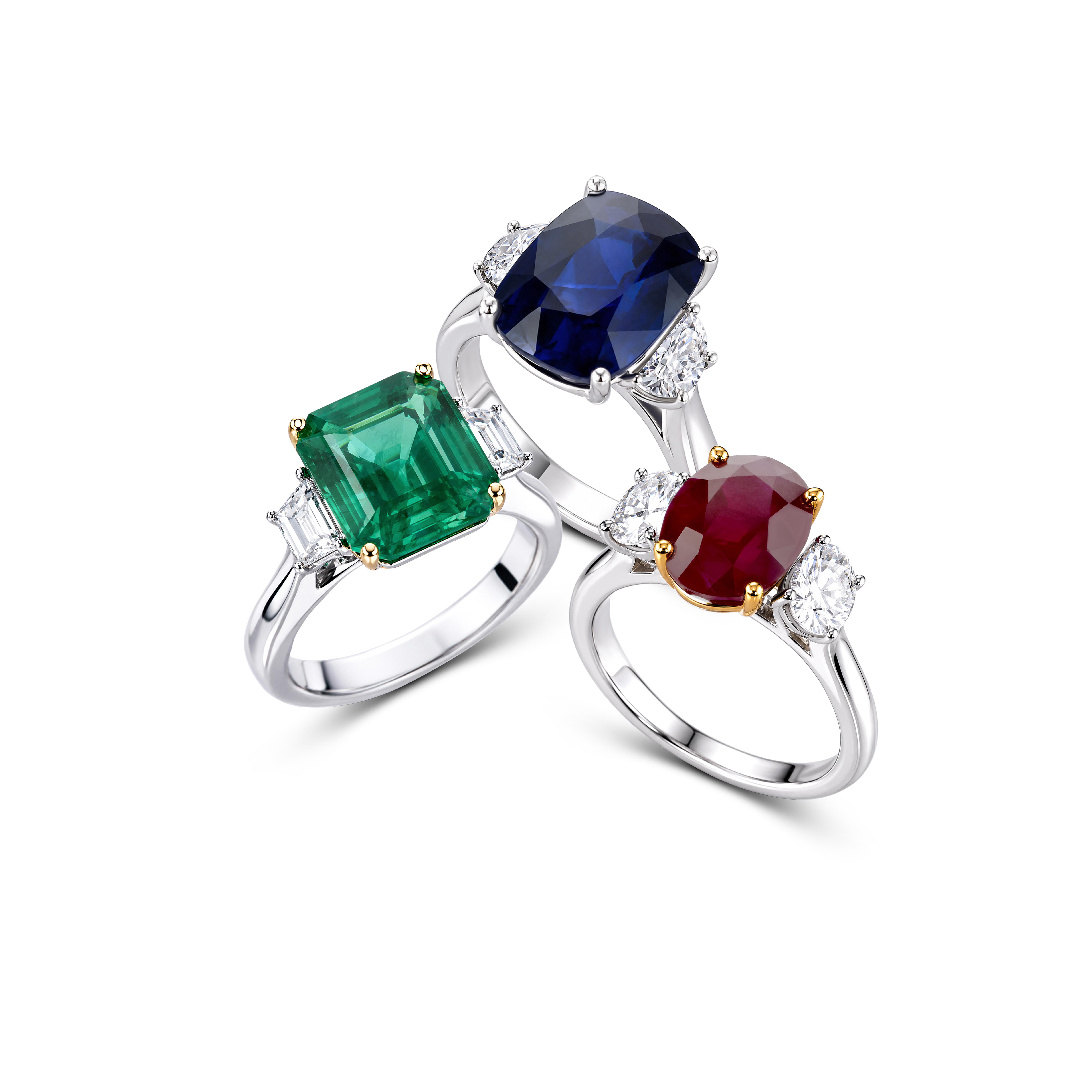 Three PJ Watson gemstone rings featuring an emerald, blue sapphire and ruby, each framed by white diamonds.