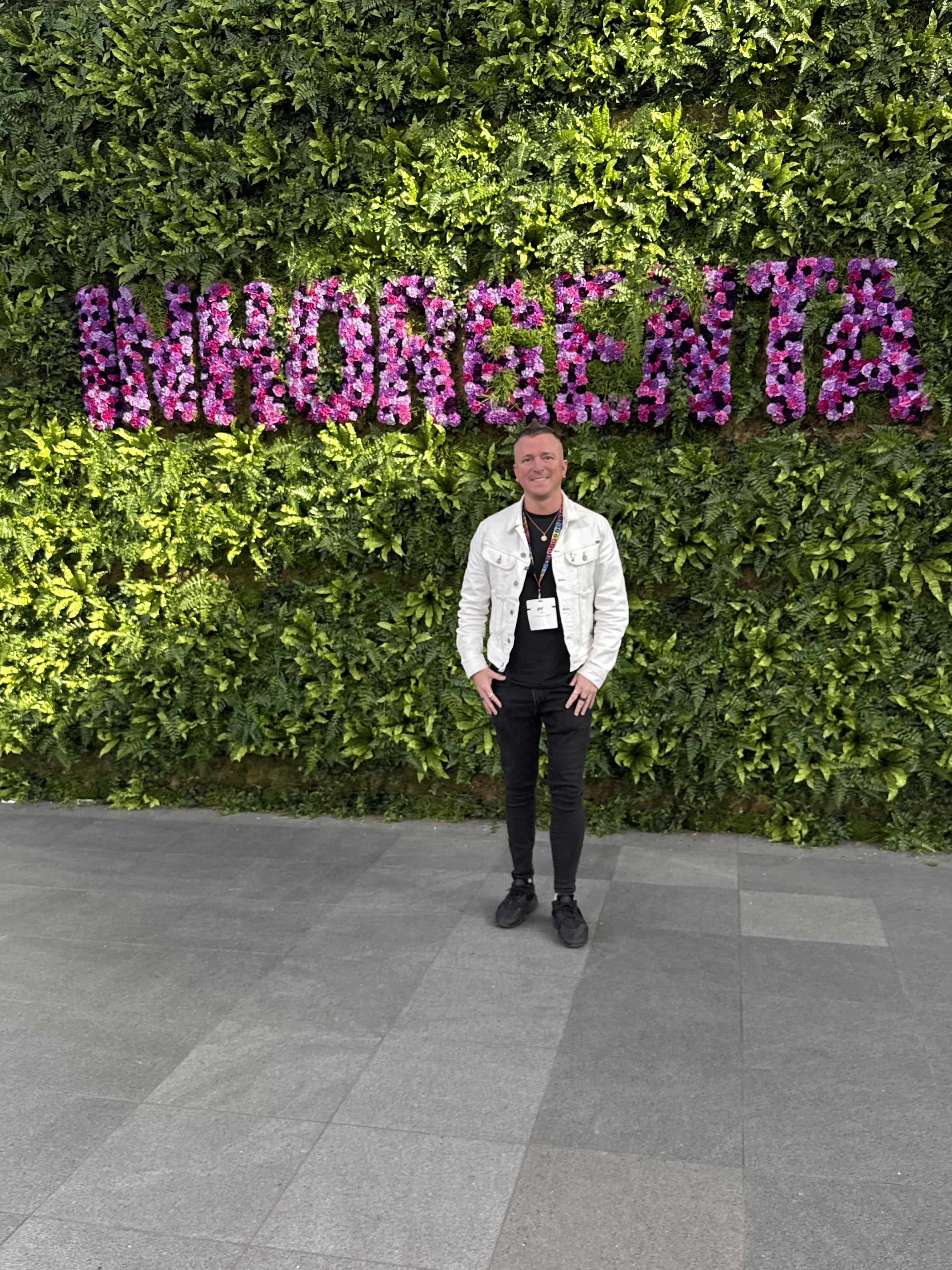 Andrew Martyniuk standing in front of a living green wall with INHORGENTA written across it in pink and purple flowers