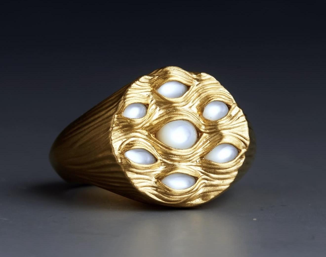 Textured gold signet ring from Kasun London’s Eyes of Many collection featuring multiple eye-shaped settings filled with white pearls across the face of the design.