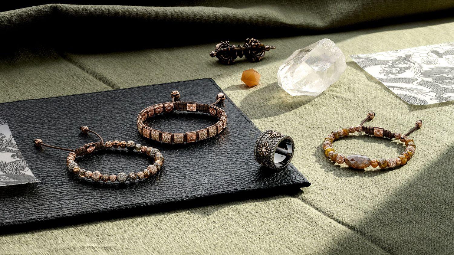 Still life of three Shamballa Jewels bracelets and an ornate statement ring arranged with crystals on green fabric and black leather