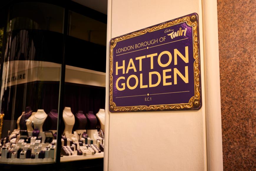 Purple and gold “Hatton Golden” sign displayed outside Solitaire Jewellers in Hatton Garden.