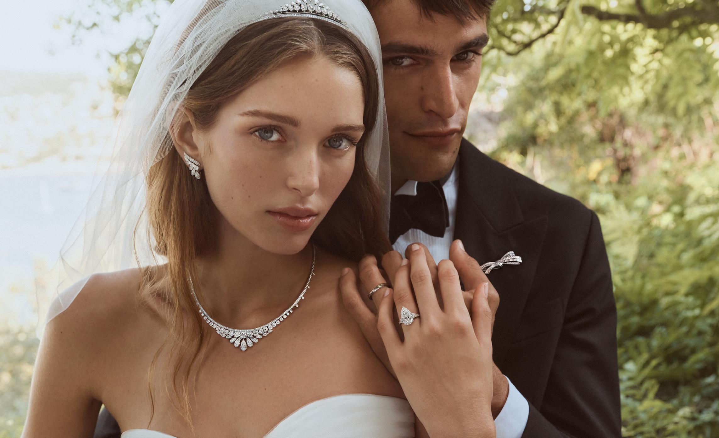 Bride and groom standing closely together in a garden while displaying Graff diamond jewellery