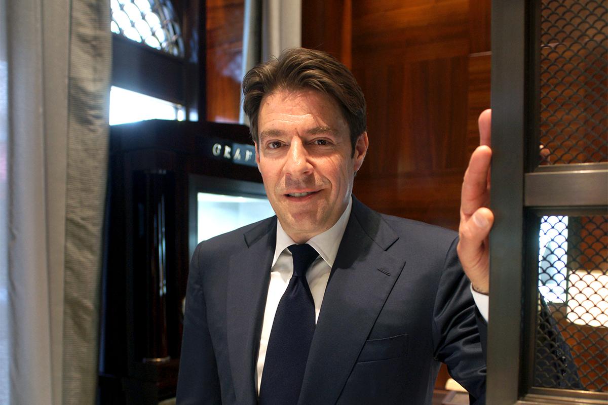 François Graff wearing a navy suit and standing beside a display inside a Graff jewellery boutique