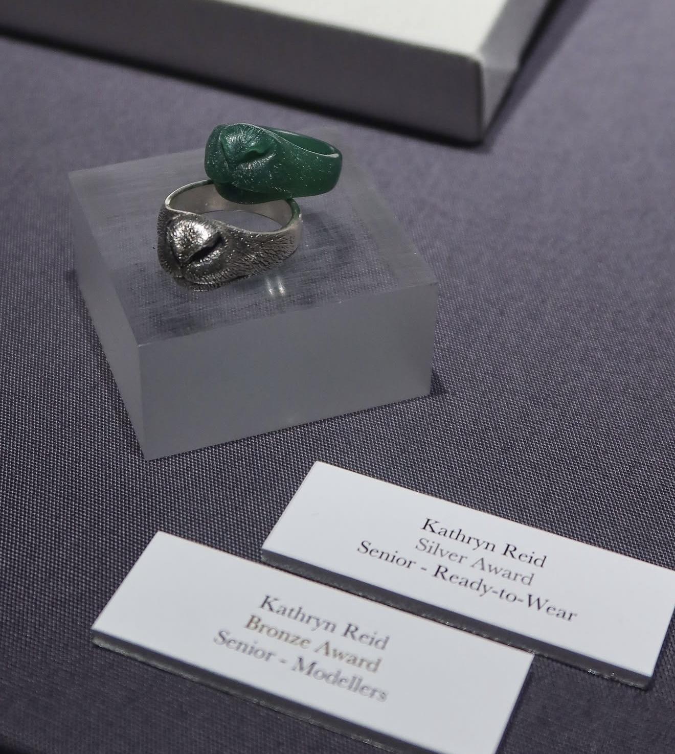 Kathryn Reid’s silver Sheep Nose Ring displayed beside its green hand-carved wax model and labels for her silver and bronze Craftsmanship and Design Awards