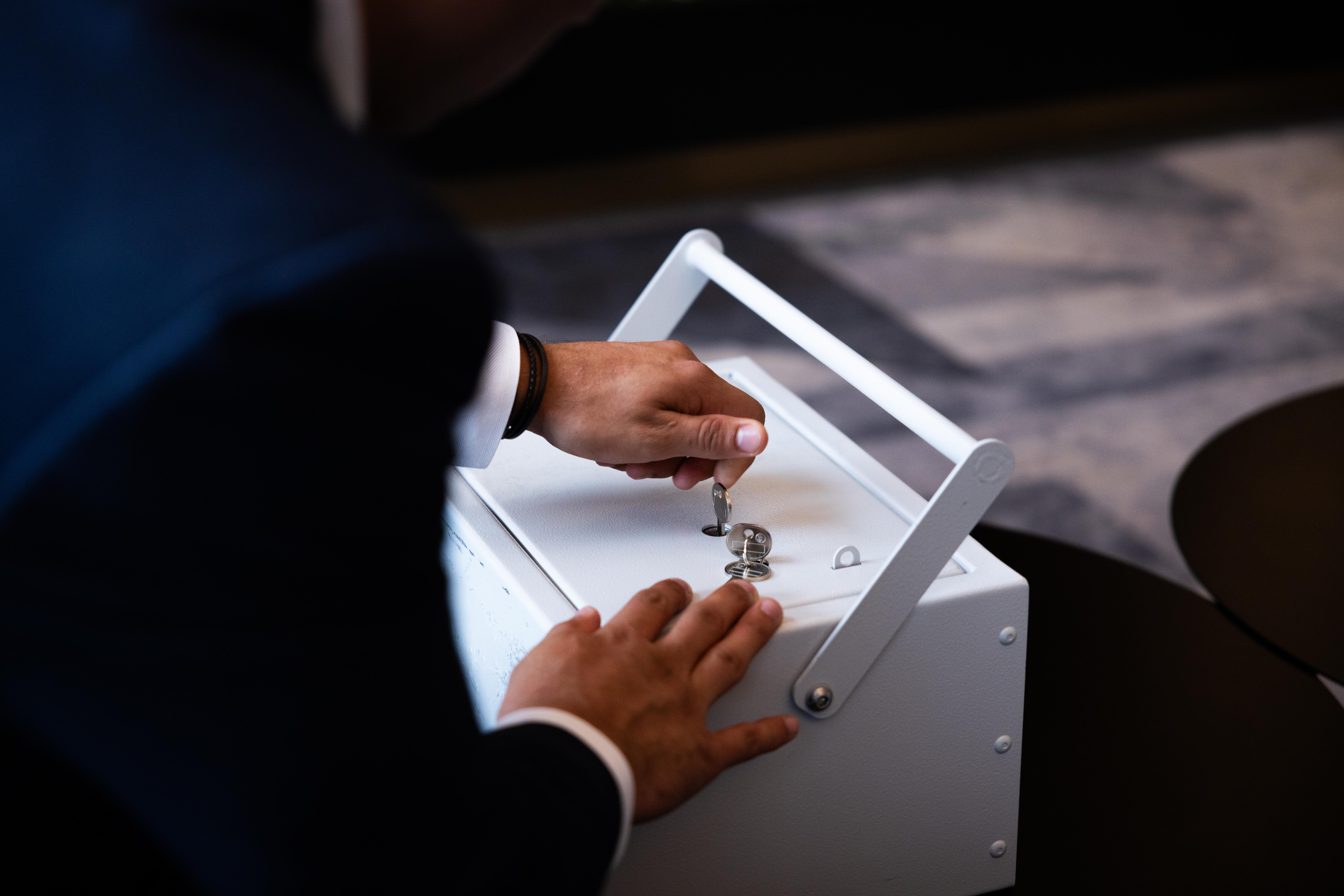 A portable Ultra-Vault safe deposit box being opened using a key, demonstrating the dual-key security system used for secure storage and access to valuables