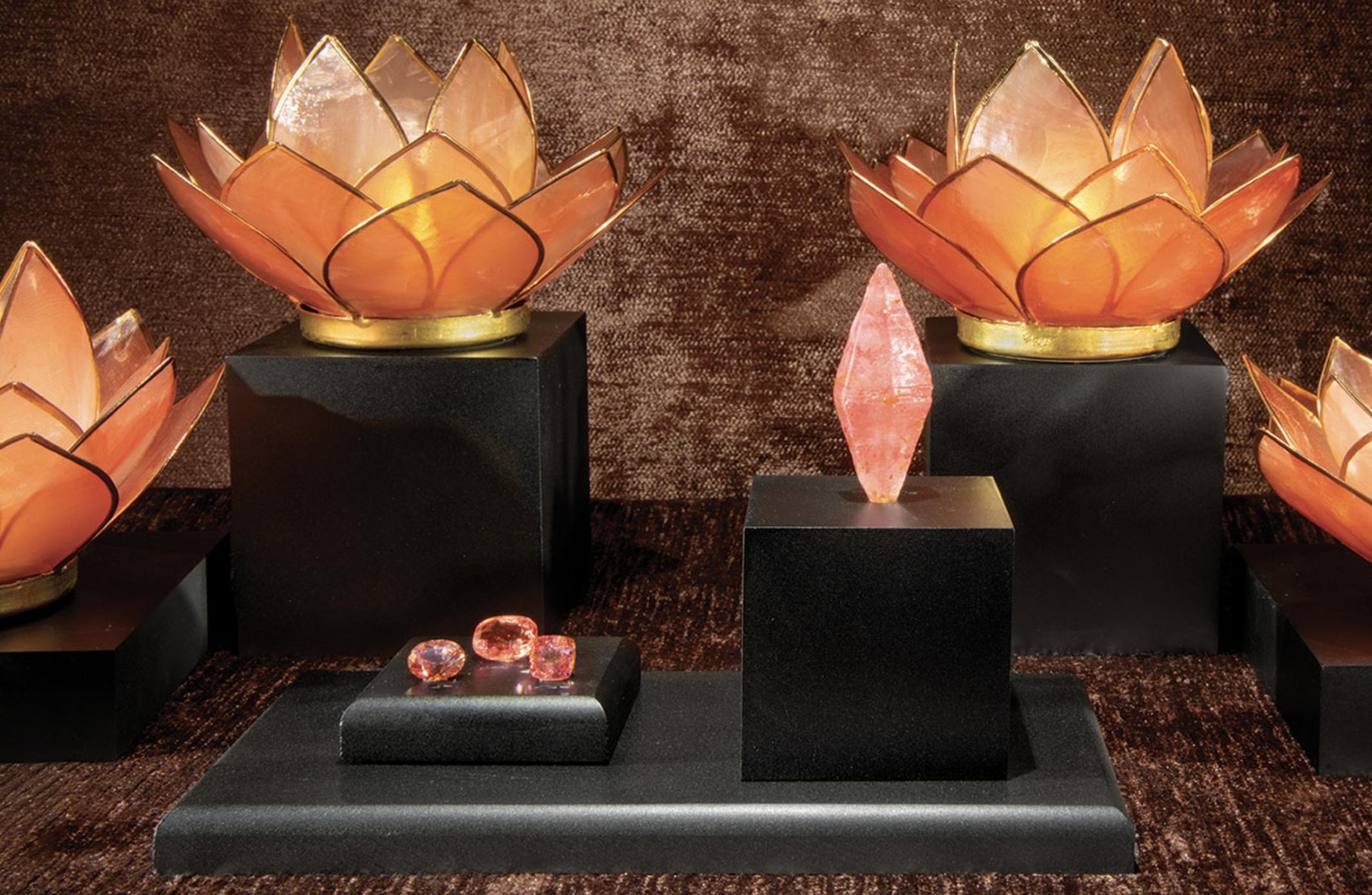 Padparadscha sapphires displayed with a crystal specimen, inspired by lotus blossoms and sunset hues.