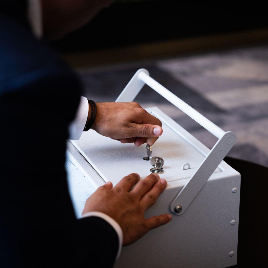 A person unlocking a white portable secure storage box with a key, illustrating UltraVault&rsquo;s mobile vault service.