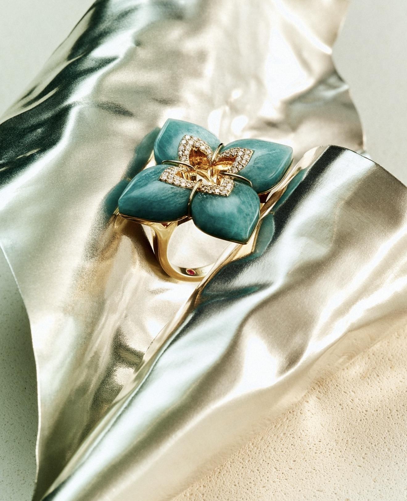 Roberto Coin Venetian Princess ring with turquoise-coloured floral petals, diamond details and yellow gold set on metallic fabric.