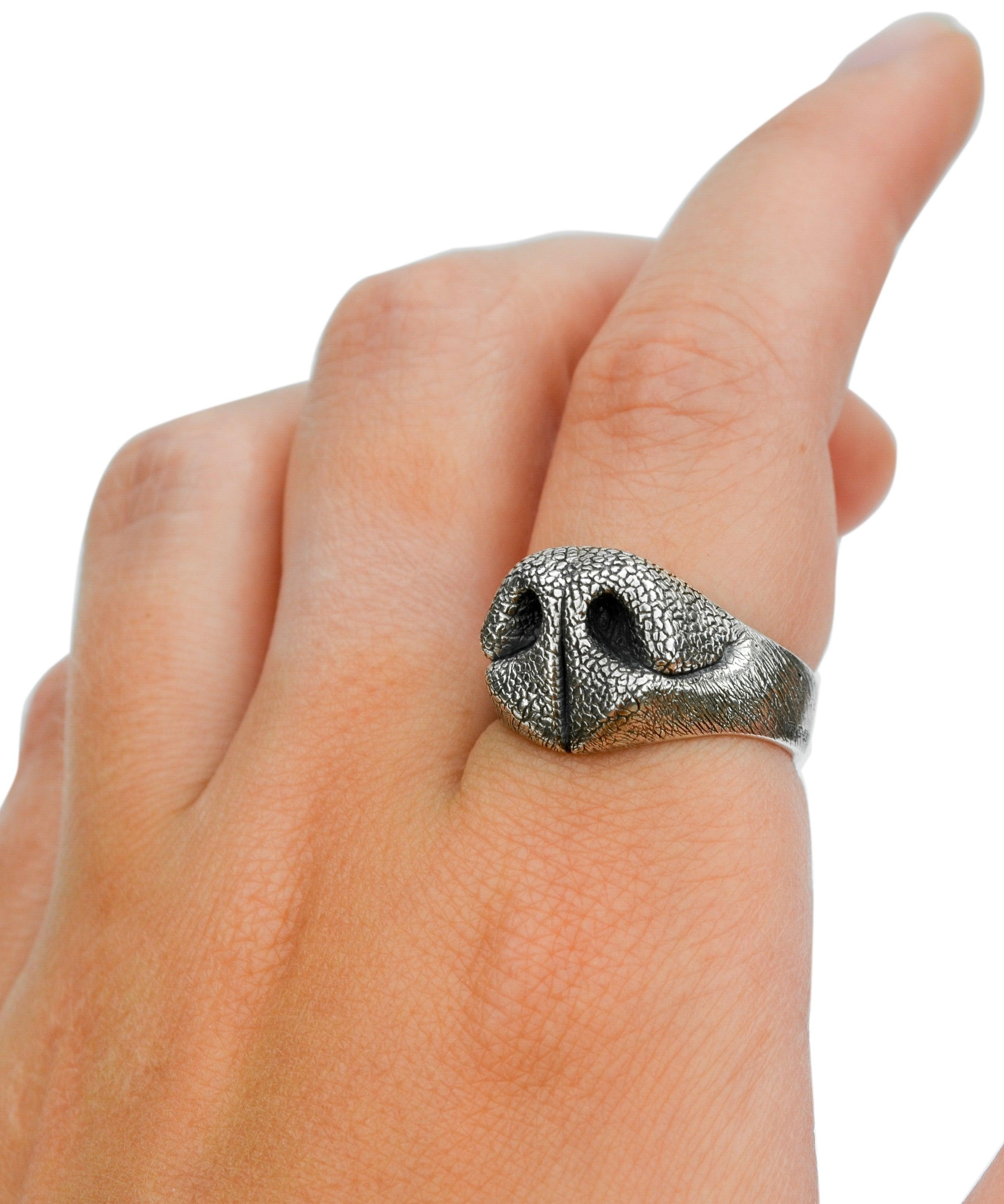 Kathryn Reid’s textured sterling silver Dog Nose Ring photographed against a white background with its reflection visible below