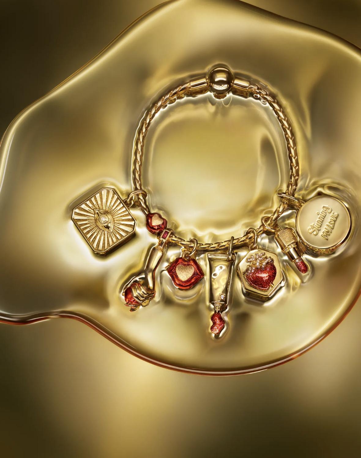 Gold necklace with a small red enamel lips charm and a larger radiant eye charm set with a central lab-grown diamond.