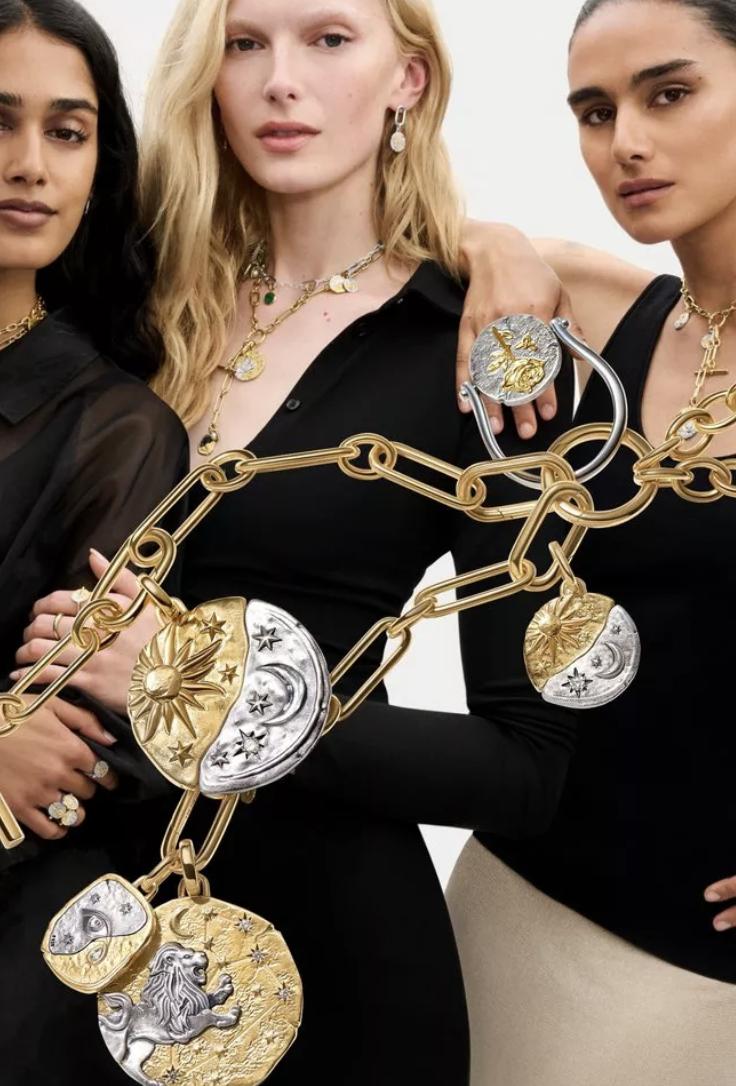 Three models wearing layered Pandora Talisman jewellery, surrounded by enlarged gold and silver zodiac and celestial medallions