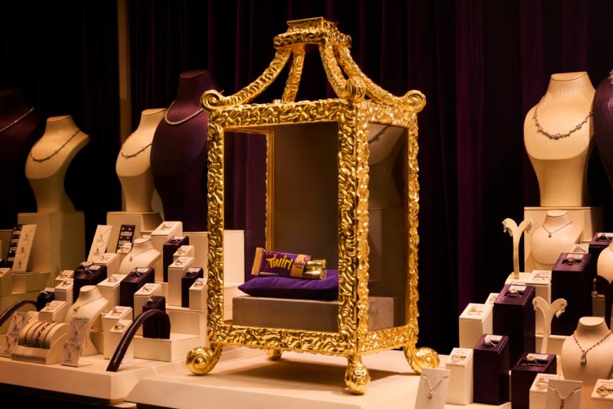 Gold-plated Cadbury Twirl displayed on purple velvet inside an ornate golden cabinet in the window of Solitaire Jewellers