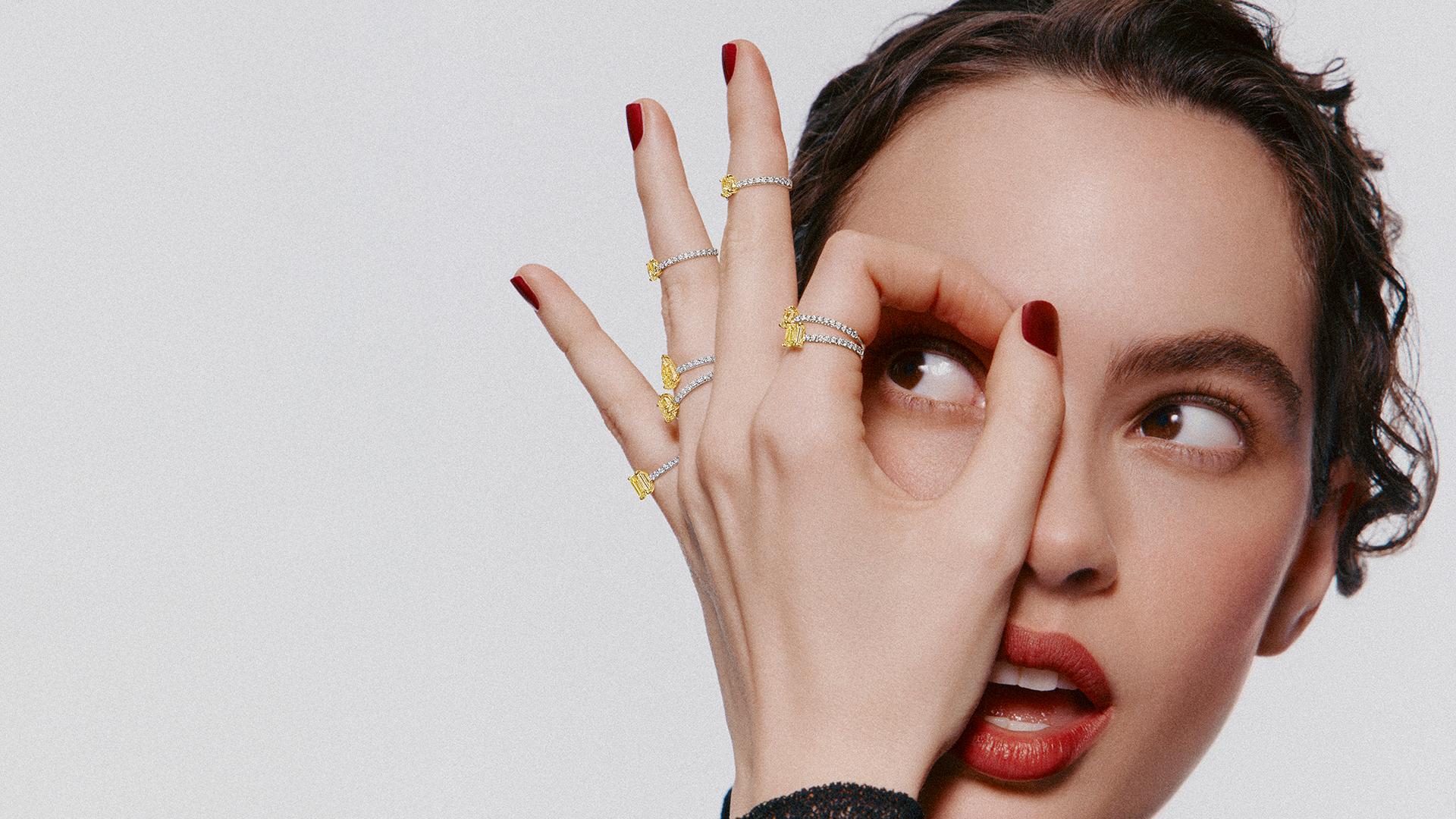 Model wearing multiple yellow and white diamond rings from Graff’s Foufou collection, featuring stackable designs with fancy yellow diamonds set on pavé bands