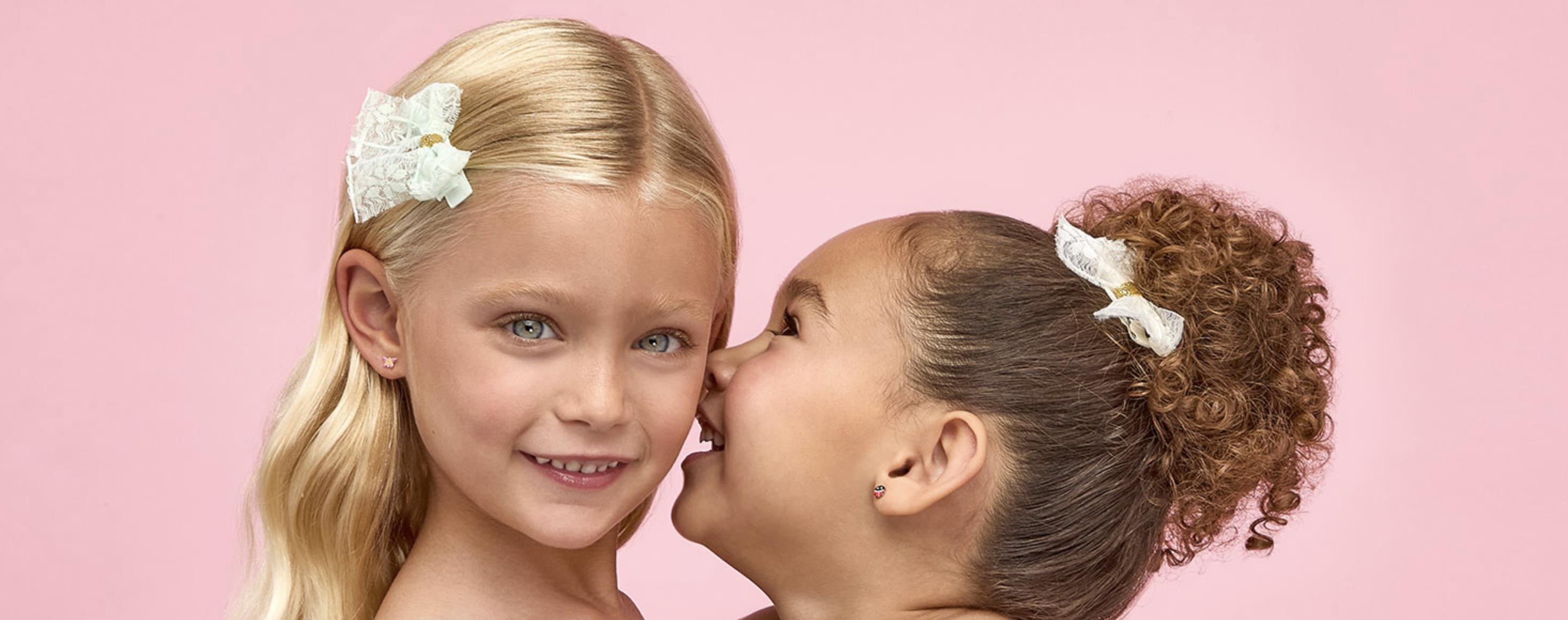 Two children wearing Inverness piercing earrings, highlighting professional ear piercing for young customers.