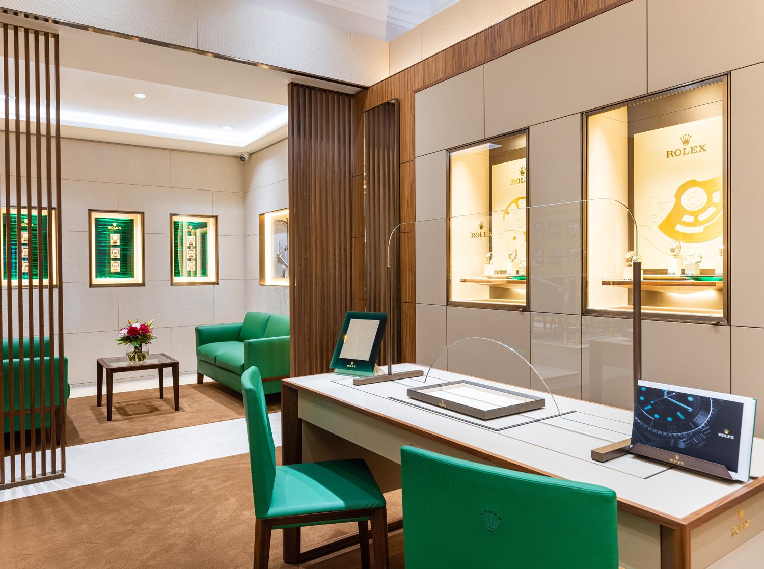 Interior of the Rolex showroom at Wakefields Jewellers in Horsham with display cases, consultation desk and green seating area.