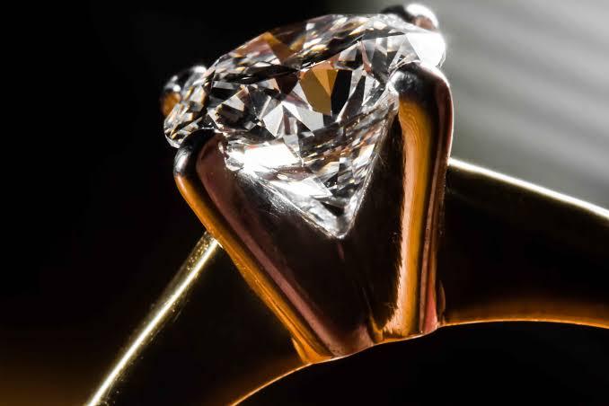 Close-up of a large colourless gemstone held in the gold setting of a ring