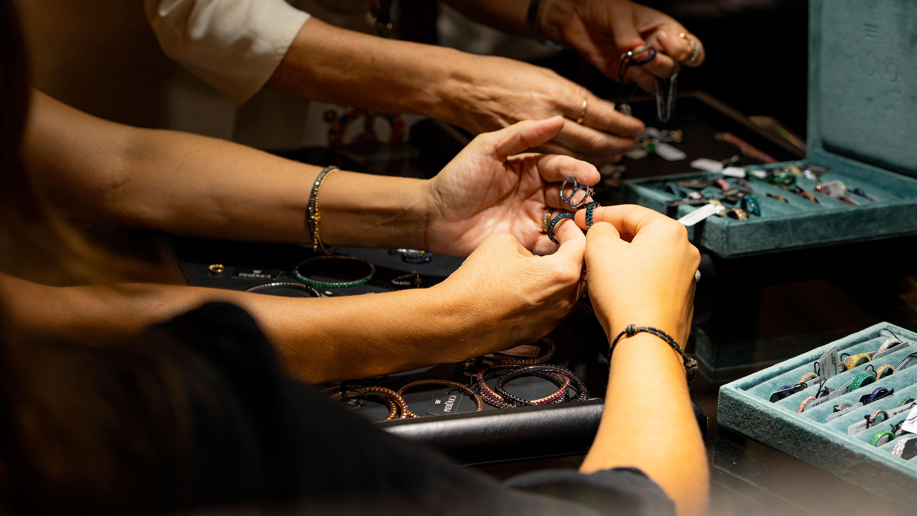 Jewellery professionals handling rings beside trays of colourful finished jewellery at the Vicenzaoro trade show