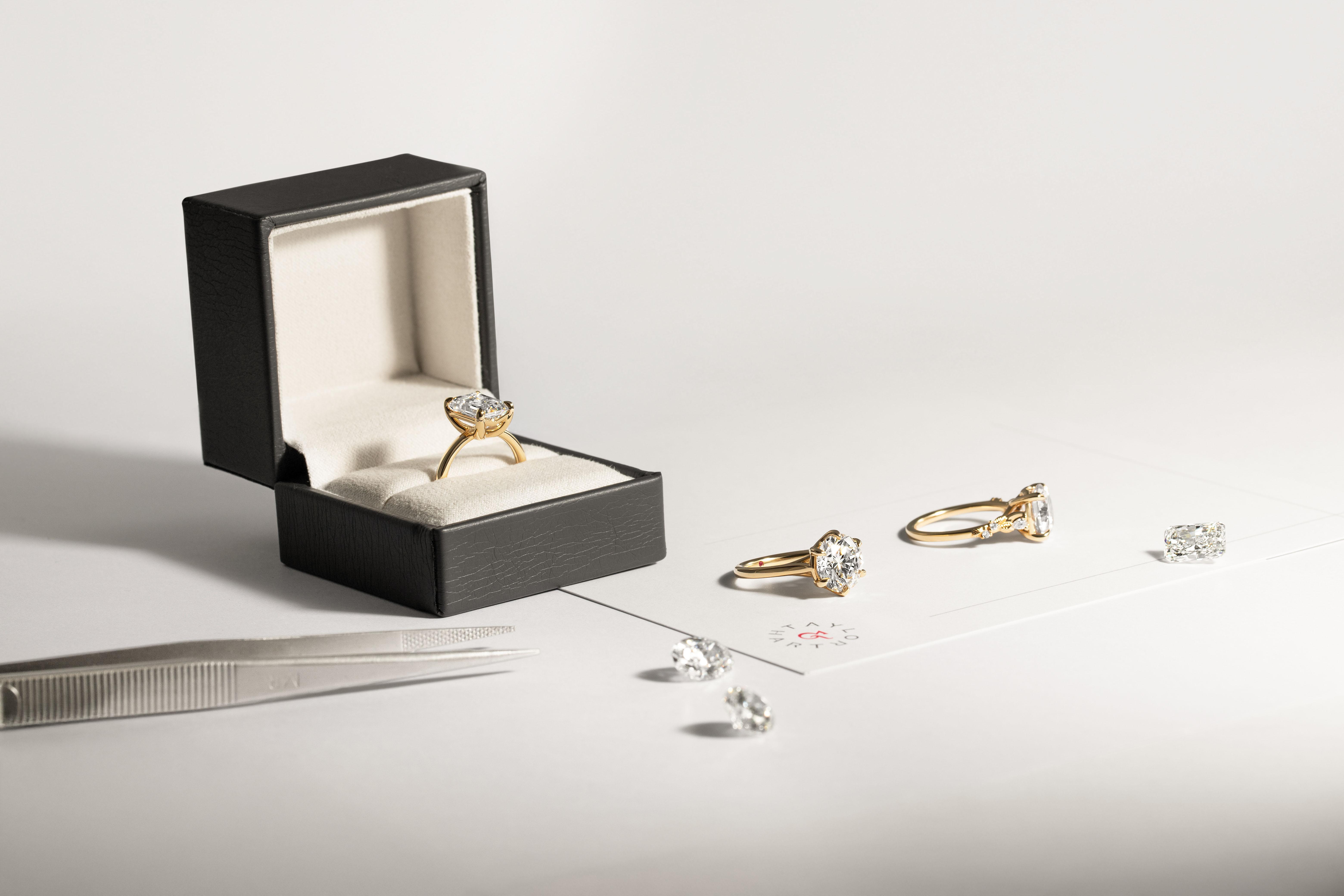 Engagement rings, loose diamonds and jewellery tools arranged on a work surface showing the ring design process