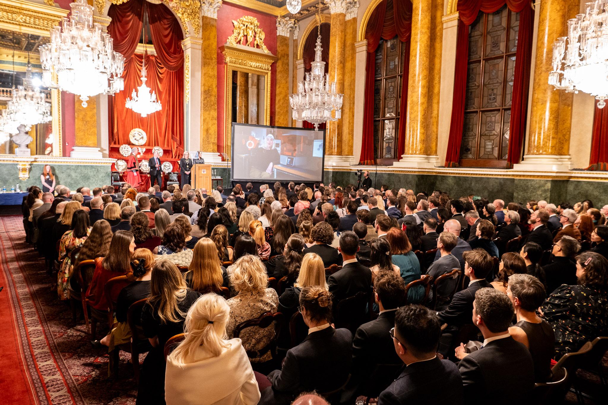 A large audience seated beneath crystal chandeliers in an ornate ceremonial hall during the 2026 Goldsmiths’ Craft & Design Council Awards