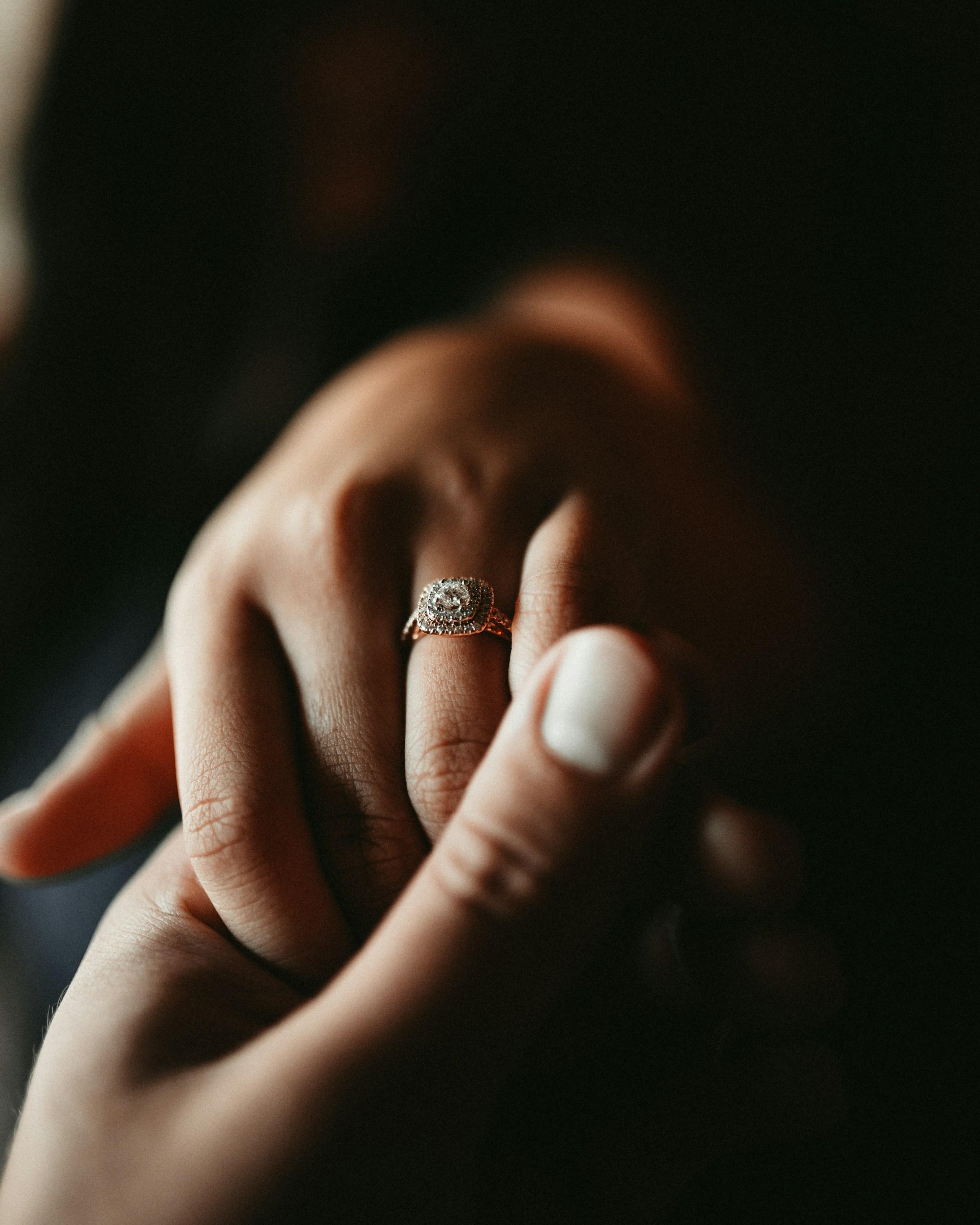 Person wearing a diamond ring on their hand. Source: Unsplash