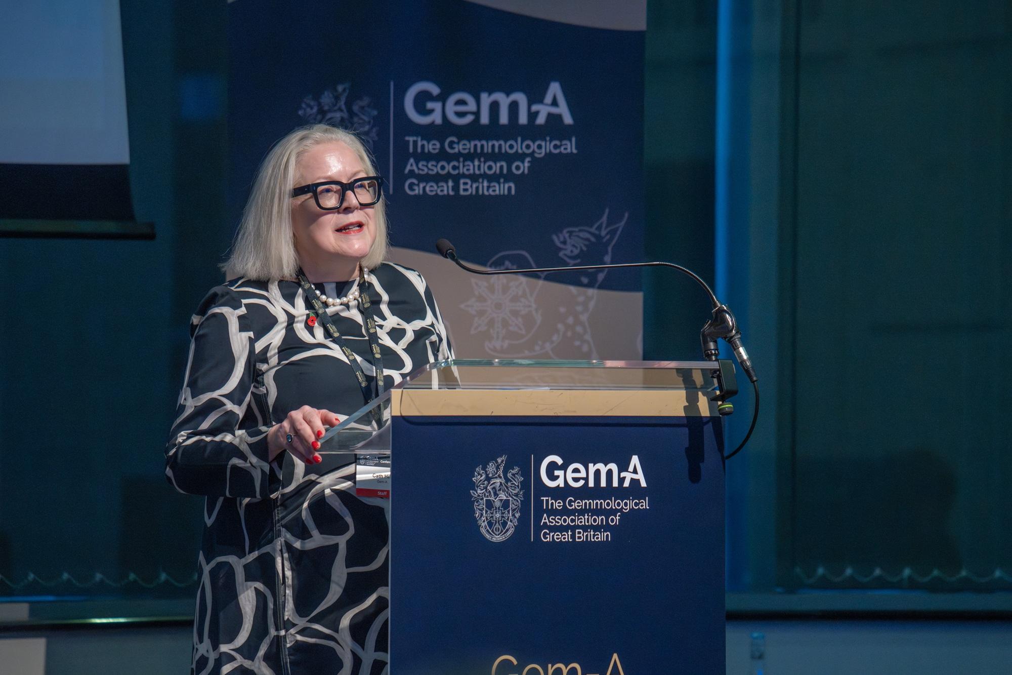 Gem-A CEO Cath Hill speaking at a podium during the Gem-A Conference 2025.