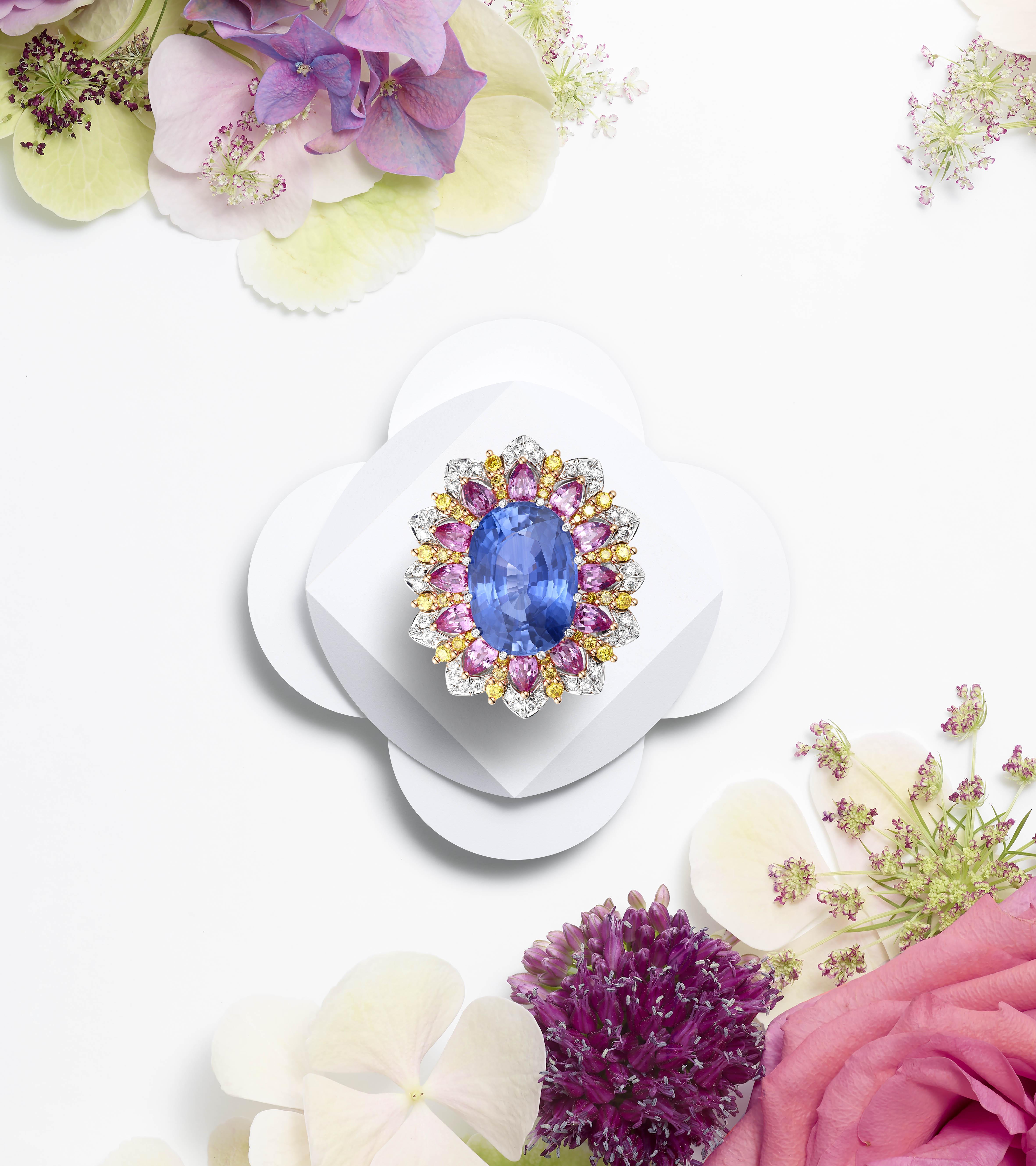 Blue cabochon gemstone ring surrounded by yellow sapphires and diamonds styled with colourful flowers
