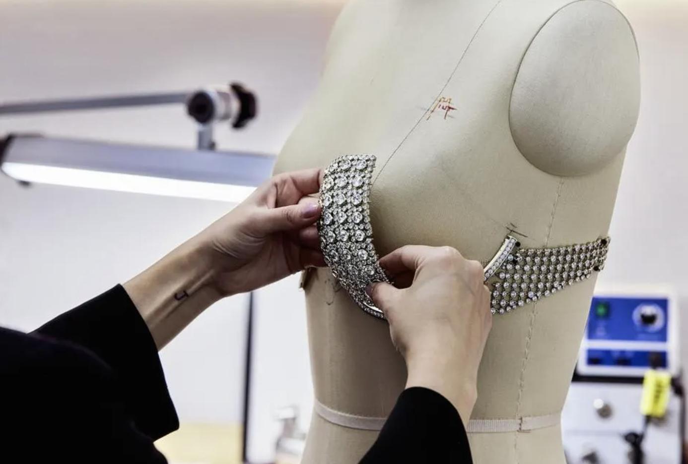 A jewellery artisan adjusts a diamond covered section of the Angel Fantasy Bra on a dressmaker’s bust form inside the Jacob & Co. workshop