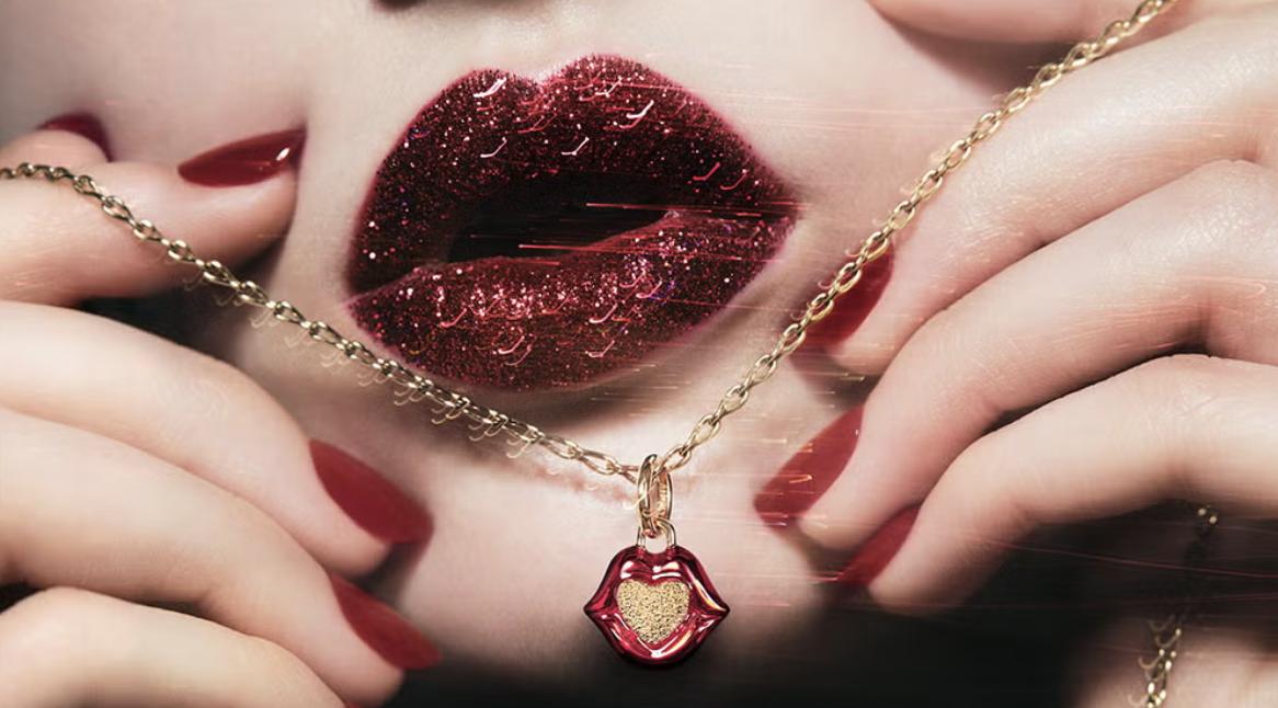 Model with glittering red lips and matching nails wearing a gold chain with a red enamel Lips of Love charm.