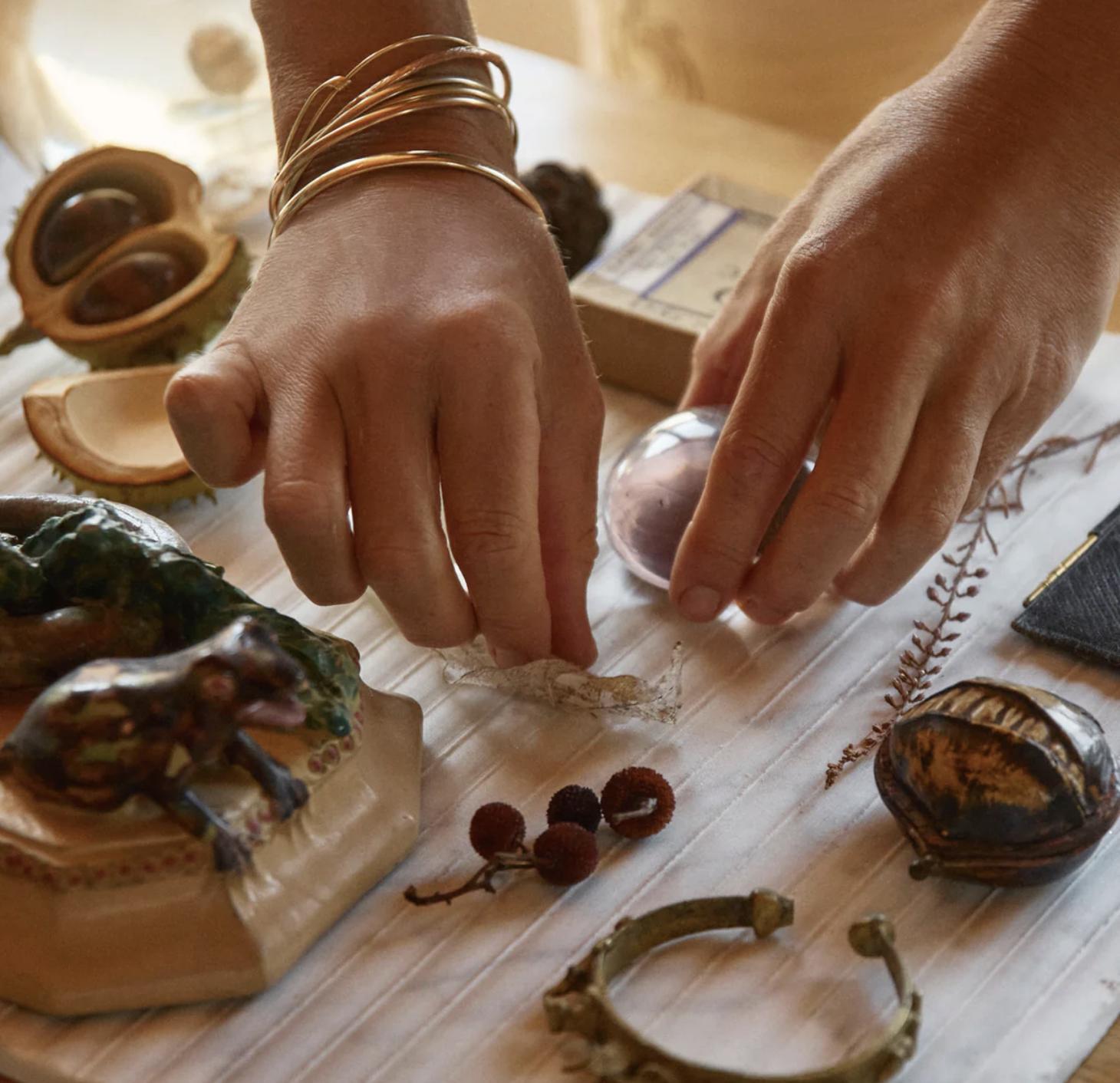 Close-up of hands arranging natural objects, stones and materials on a work surface during the design process.