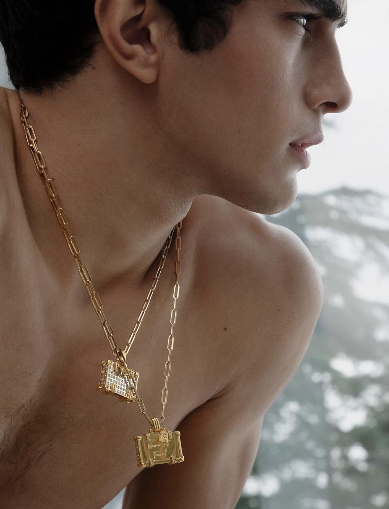 Close-up of a model wearing two layered gold chain necklaces with detailed rectangular pendants.