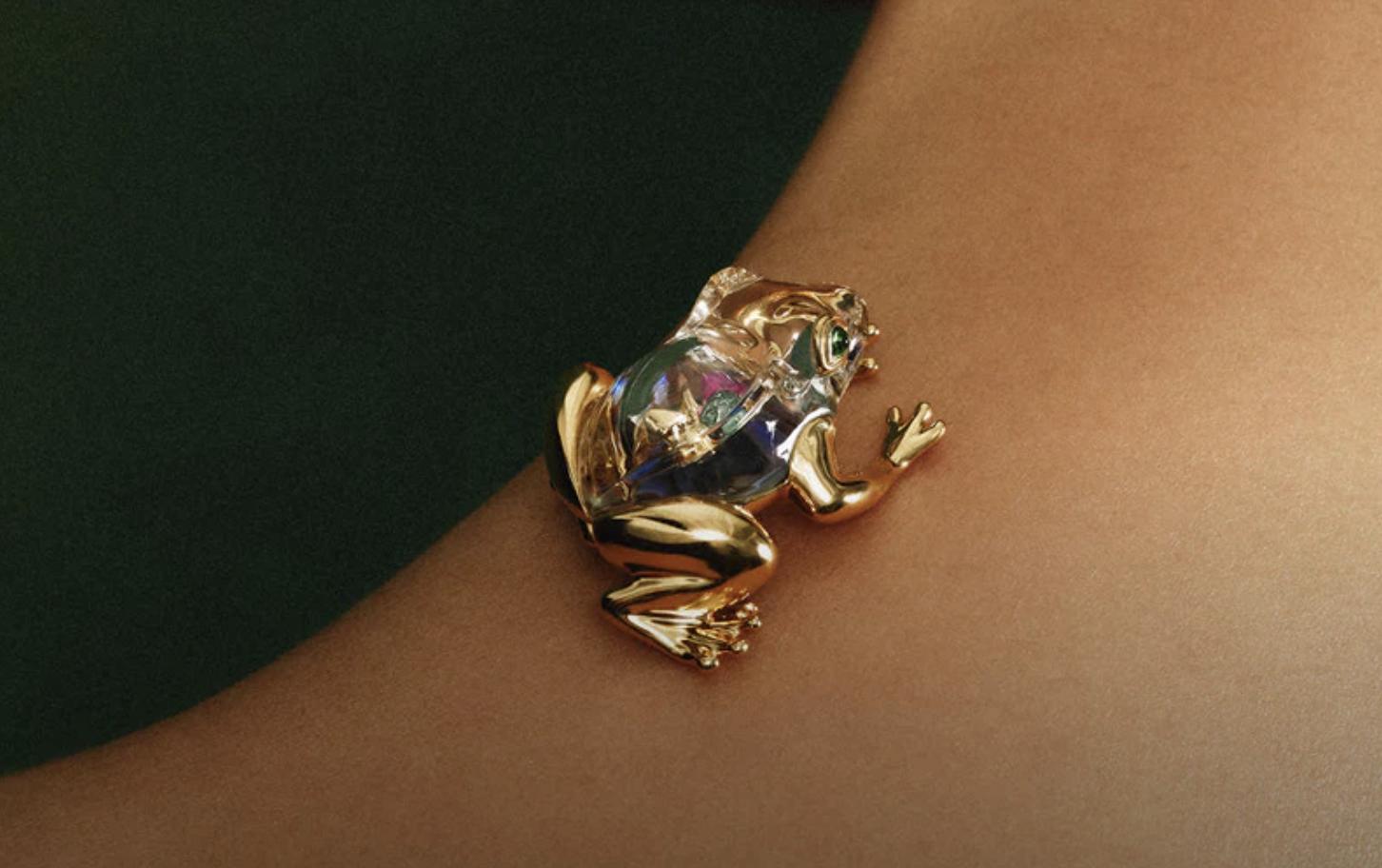 Close-up of a frog-shaped brooch in 18ct yellow gold with rock crystal and abalone, worn on the shoulder.