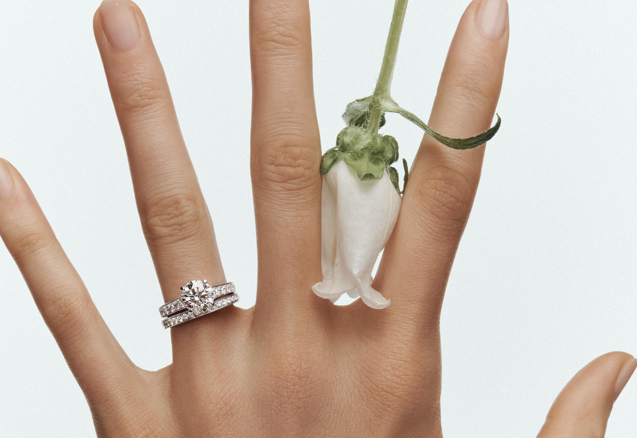 Hand displaying several Graff diamond rings in different shapes and settings against a pale background.