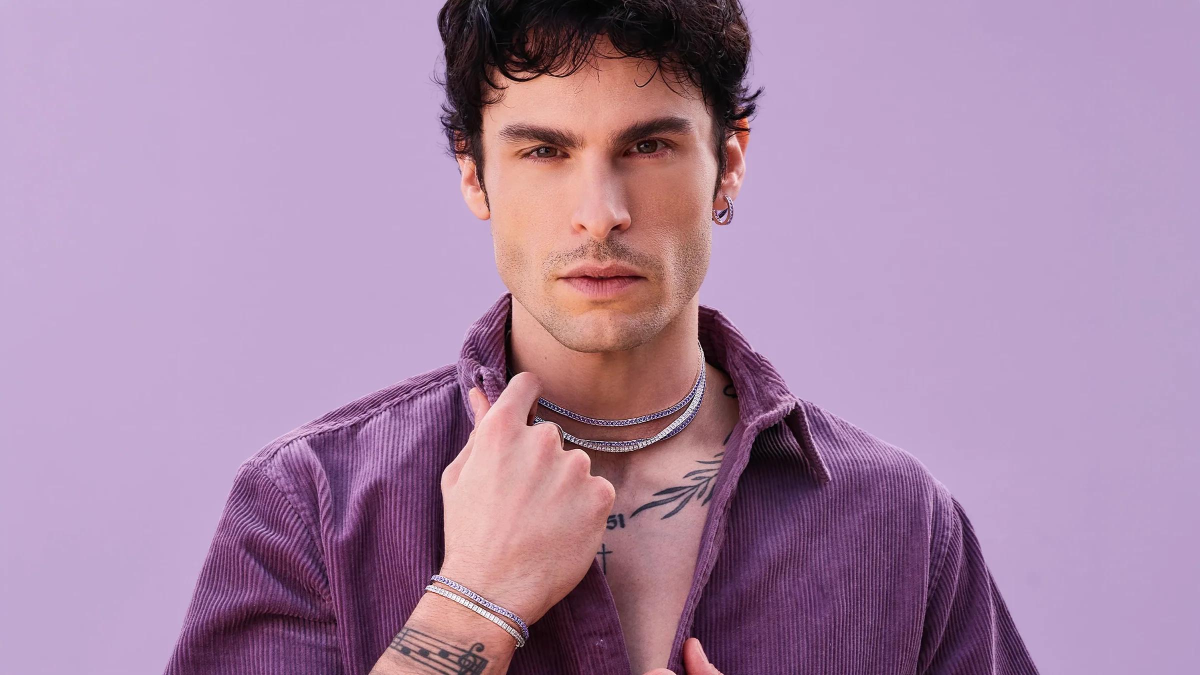 Baptiste Giabiconi wearing layered necklaces and bracelets from APM Monaco’s Printemps jewellery collection on a lilac background.