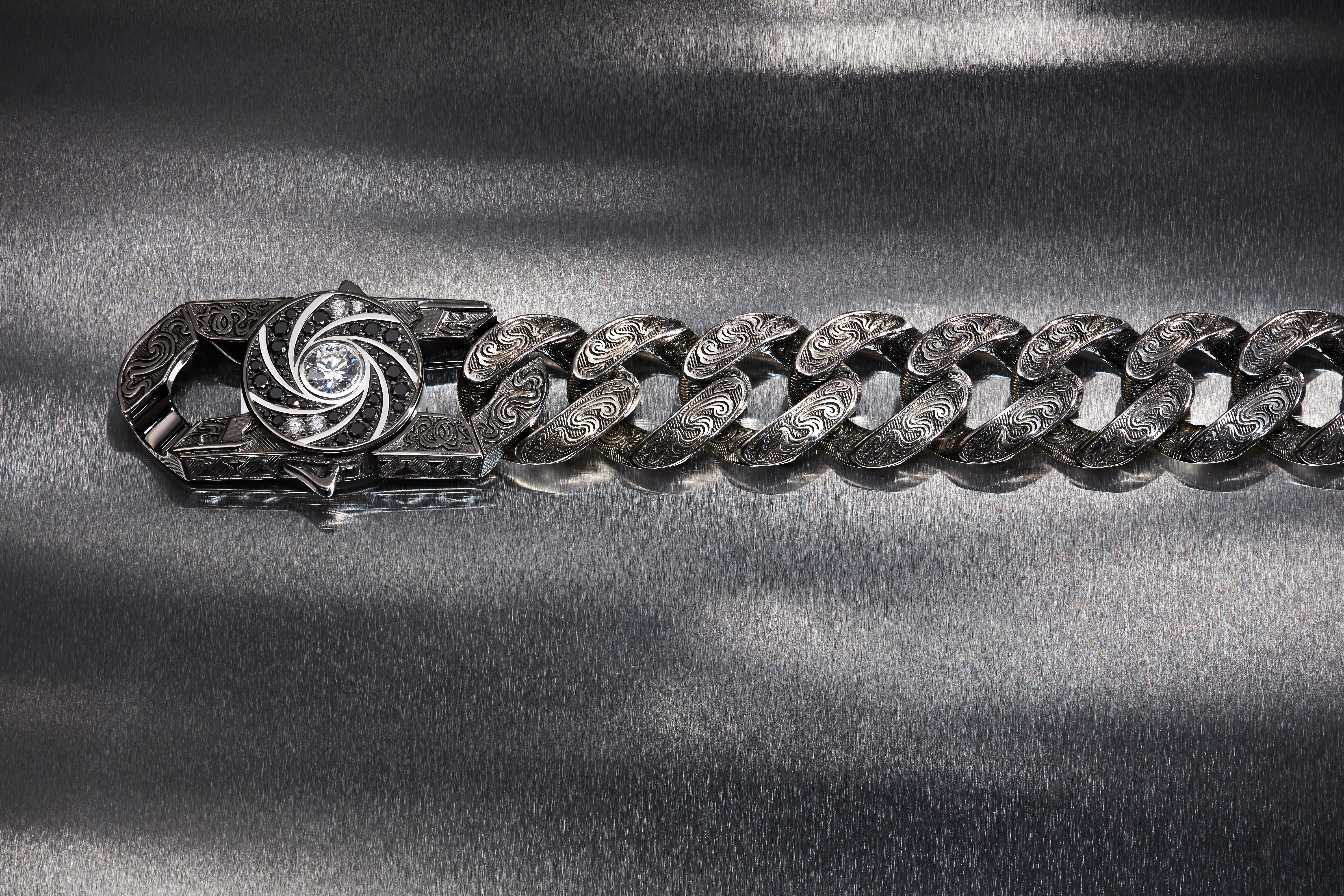Stephen Webster’s Shaken & Stirred engraved Cuban-link bracelet with a camera-shutter clasp, central white diamond and black and white diamond pavé.