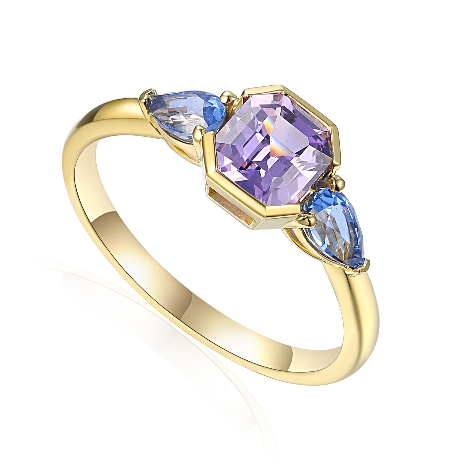 Yellow gold ring by Ntinga set with an octagonal lilac gemstone at the centre, flanked by two blue marquise-cut gemstones. The design highlights the company&rsquo;s expertise in coloured gemstones and modern jewellery styling.