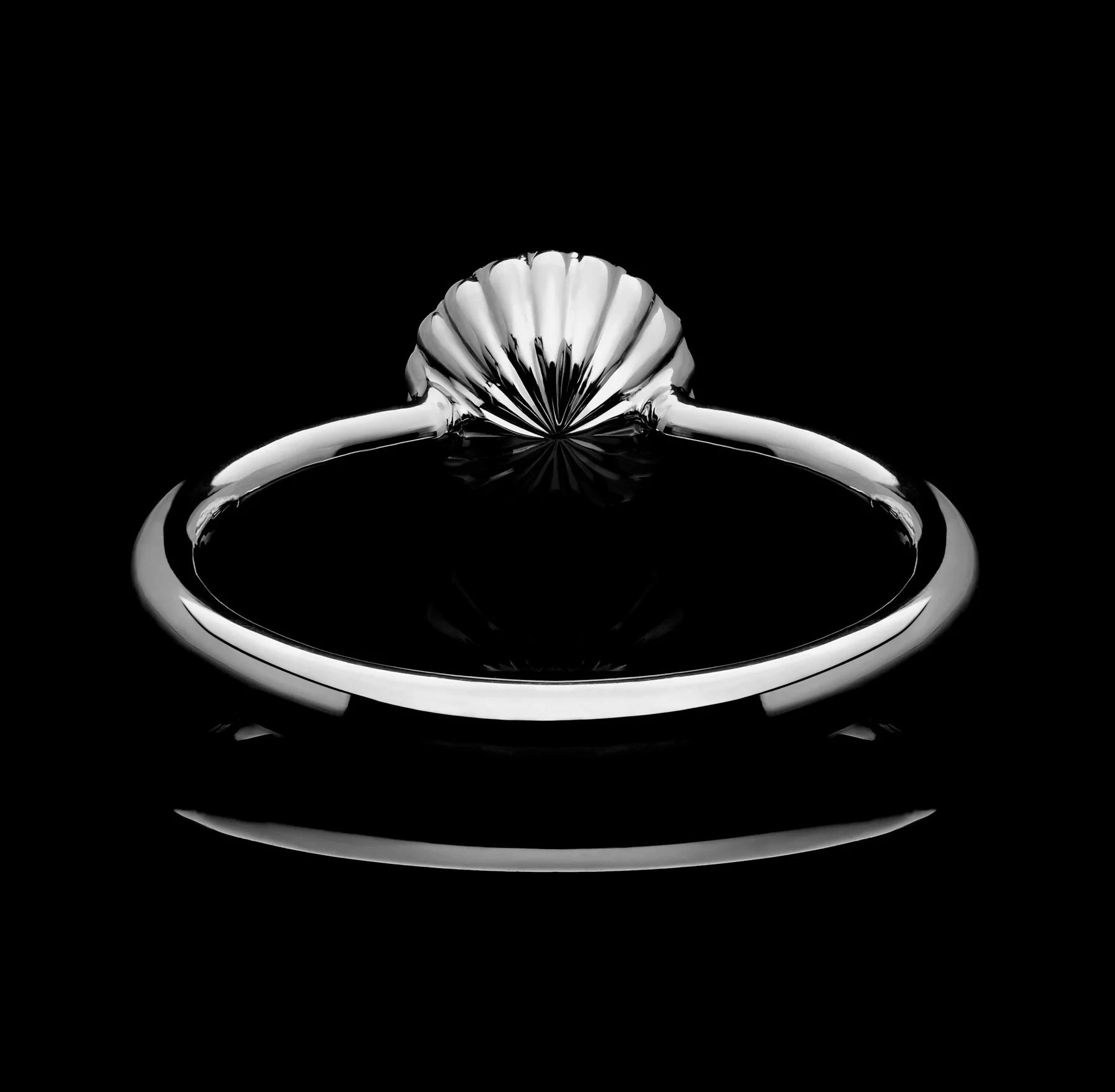 Rear view of a polished platinum Cannelé ring showing the fan-like fluted setting converging beneath the centre stone against a black background.