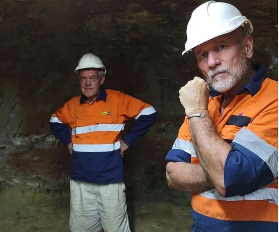 Rod Beattie and Ian Bone wearing hard hats and high-visibility work shirts inside an underground mine at Rubyvale, Queensland