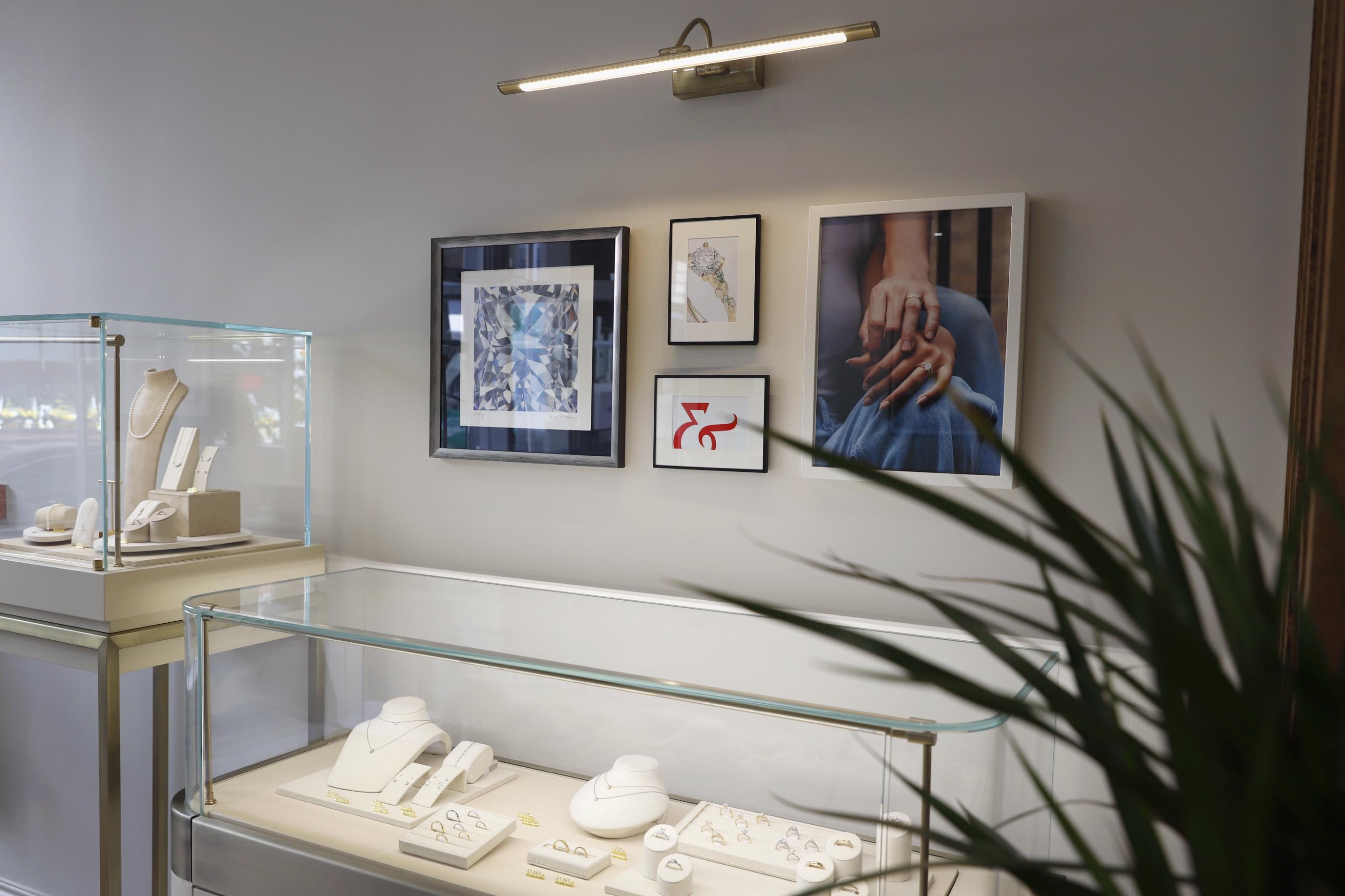 Taylor & Hart showroom interior with glass display cases showcasing engagement rings and jewellery, alongside framed artwork on the walls
