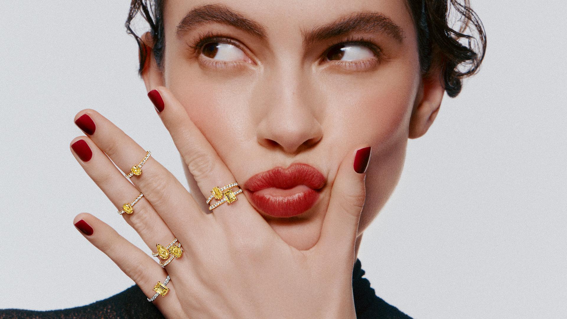 Model wearing multiple fancy yellow diamond rings from Graff’s Foufou collection, featuring stackable designs with pear, oval and emerald-cut diamonds on pavé-set bands.