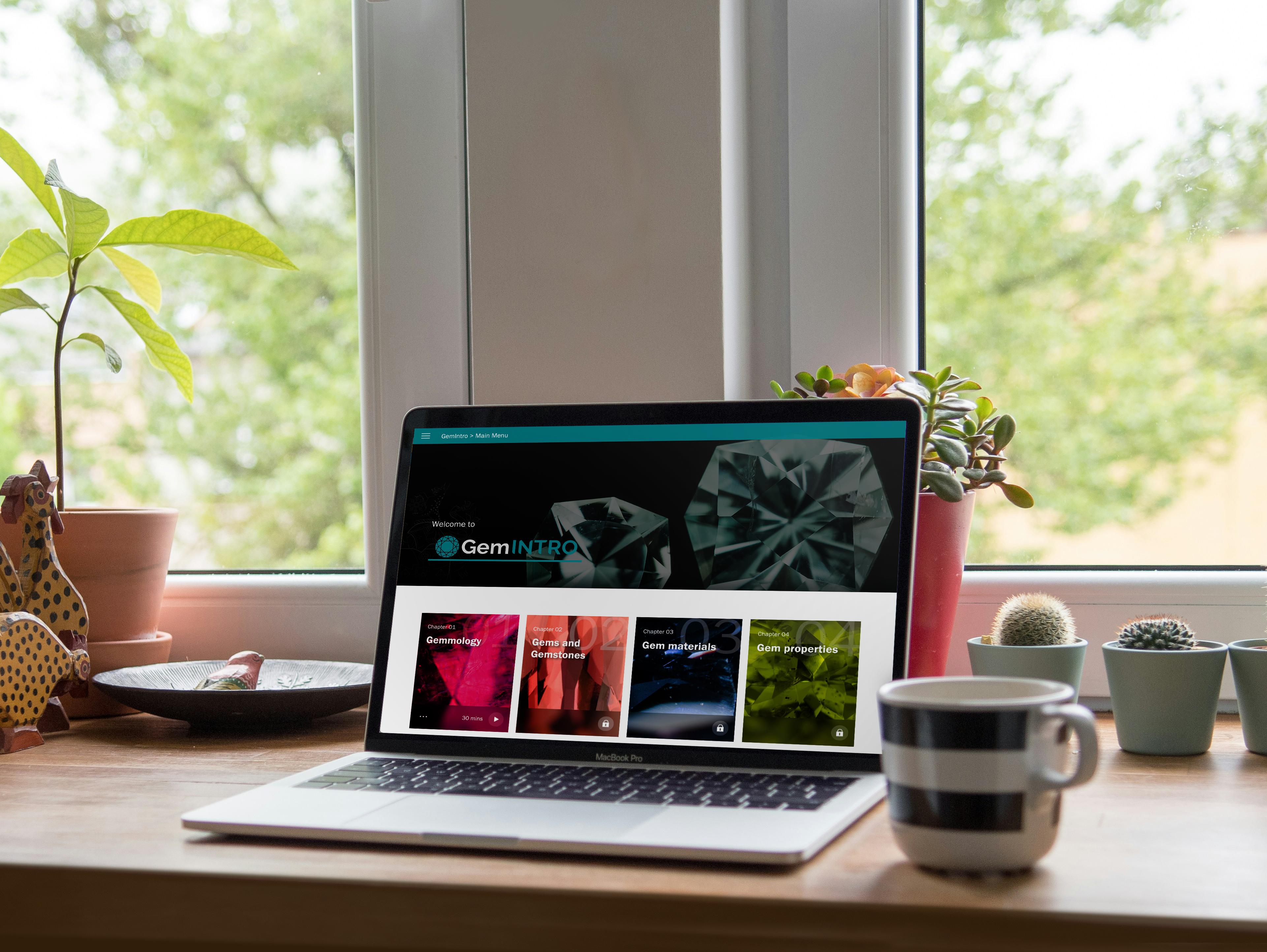 Laptop displaying the Gem-A GemINTRO online course interface on a desk, with learning modules visible on screen.