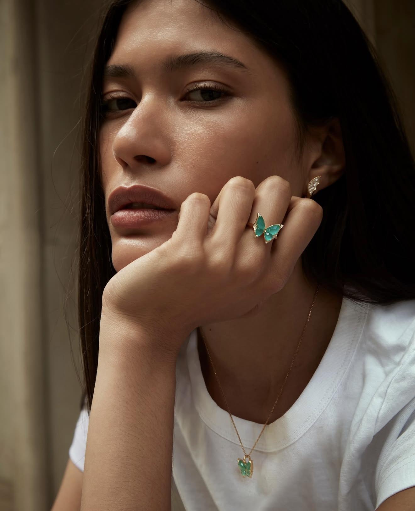 Model wearing Stephen Webster Fly By Night Mini butterfly pendant and matching ring in Light Green Agate Crystal Haze with diamond detailing.