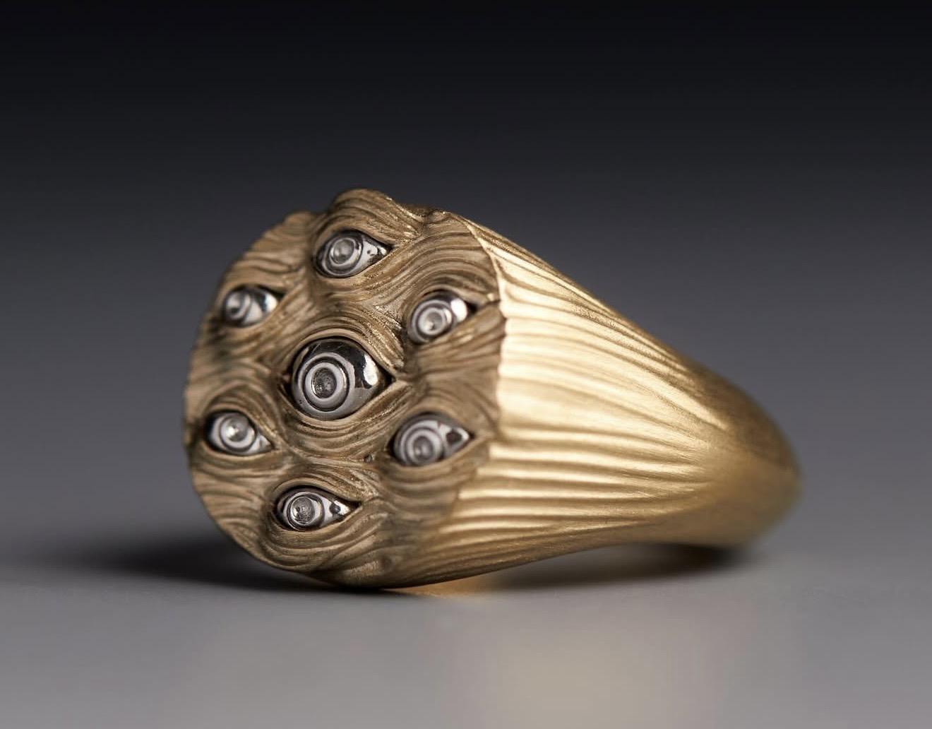 Textured gold ring featuring multiple eye motifs across the face of the design, from Kasun London’s Eyes of Many collection