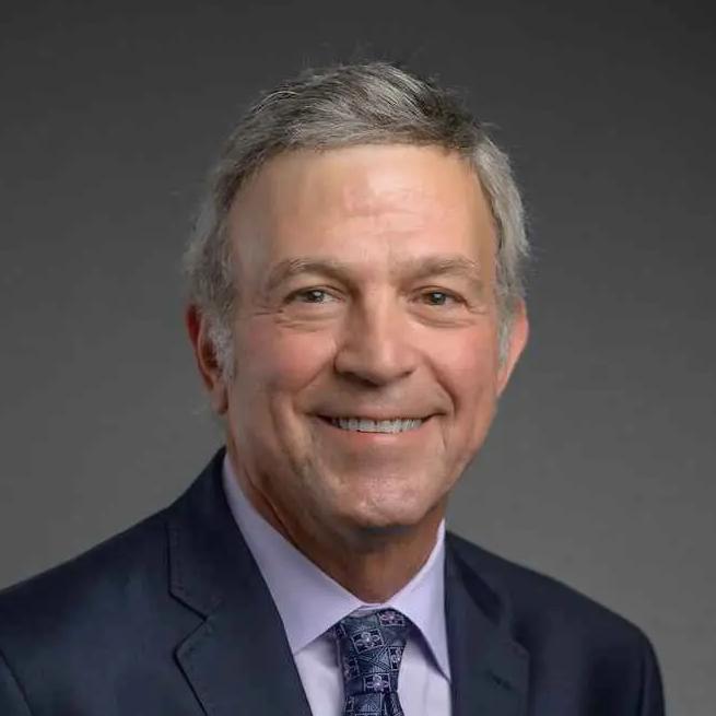 ortrait of Richard B. Drucker, Honorary President of Gem-A, wearing a suit and tie.